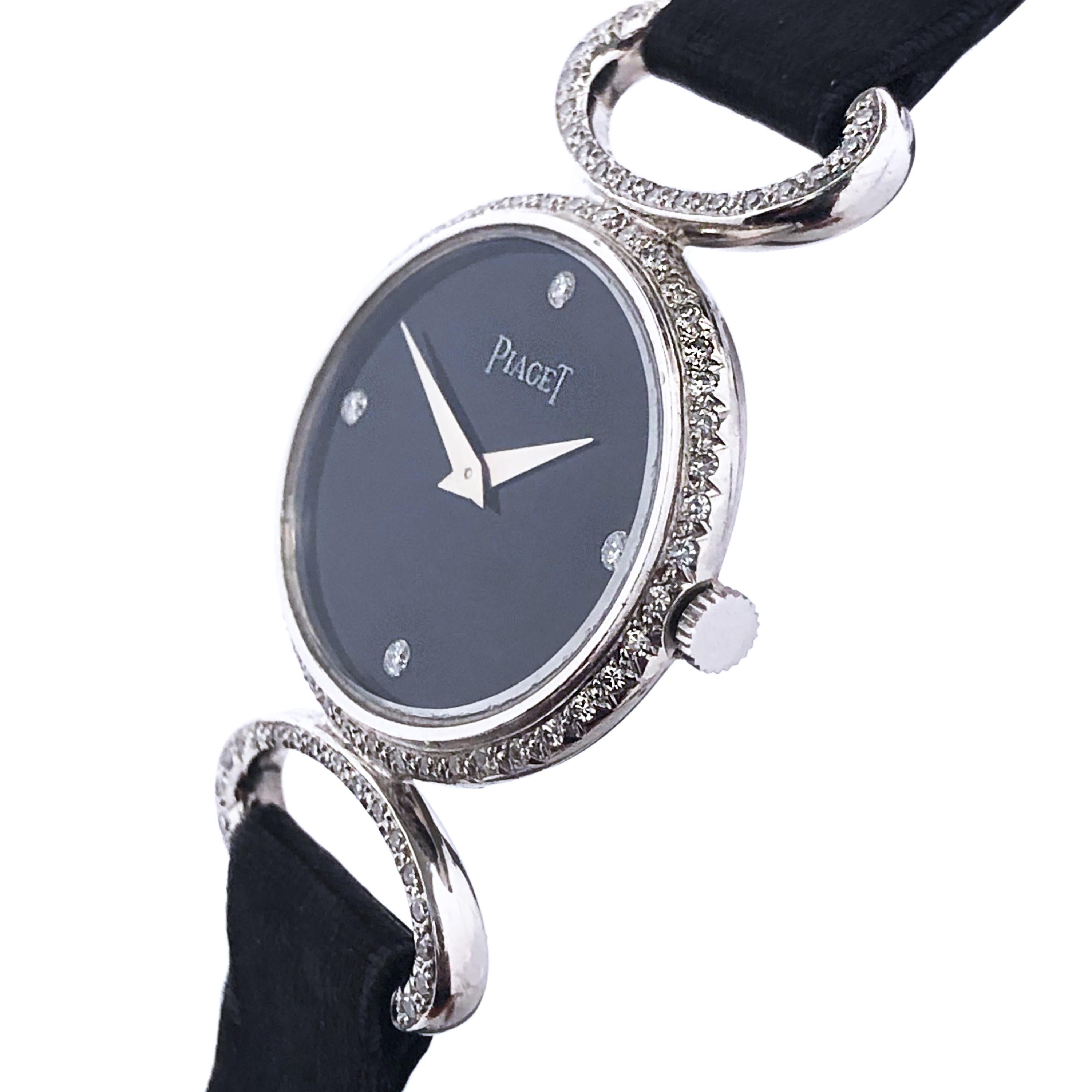 Circa 1980 Piaget Ladies Wrist watch, 27 X 22 MM Oval 2 Piece 18K White Gold case, 17 jewel Manual wind movement, Black Onyx Dial with Diamond set markers. White Gold and Diamond set Bracelet sections between original Black Satin strap sections.