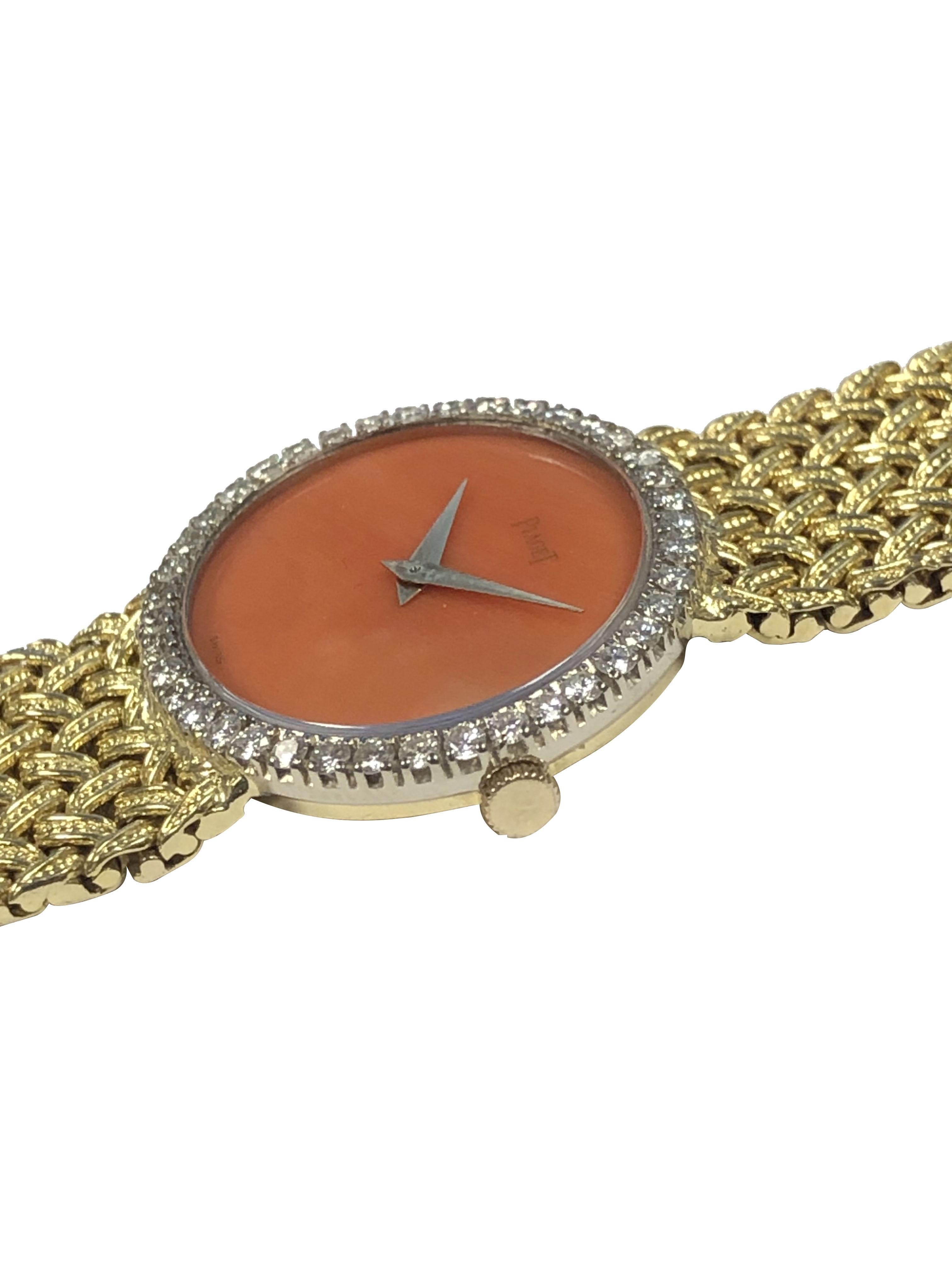 Circa 1970s Piaget Ladies Wrist Watch, 27 x 24 M.M. 18k Yellow Gold 2 piece Oval Case, Round Brilliant cut Diamonds totaling approximately 1 carat, 17 Jewel, Mechanical, Manual wind Movement, Orange - Red Coral Dial. 5/8 inch wide integrated woven