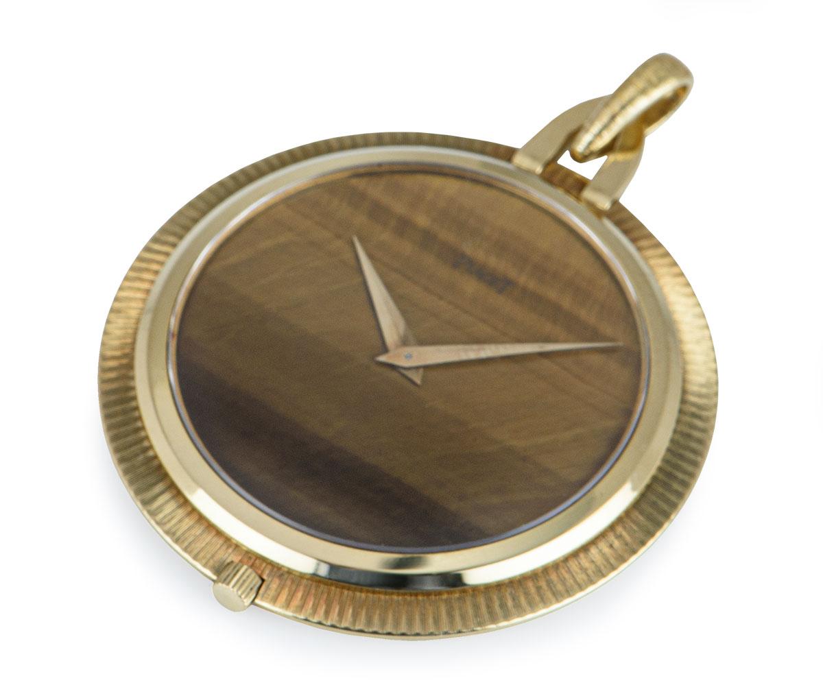 A vintage 43 mm open face pocket watch in yellow gold by Piaget. Features a tigers eye dial with gilt lance hands. Fitted with mineral glass and a manual wind movement beneath the snap-on case back which can be seen in the photos.

In excellent