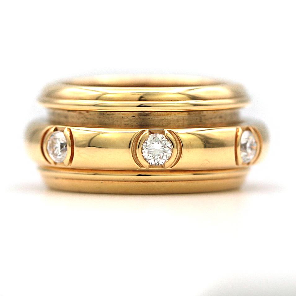 A Piaget Possession ring in 18k yellow gold, set with 7 round brilliant cut diamonds. The diamonds are set in the inner band, which moves freely in perpetual movement. Diamonds can be seen full circle. The band width is approximately 9.30mm and the