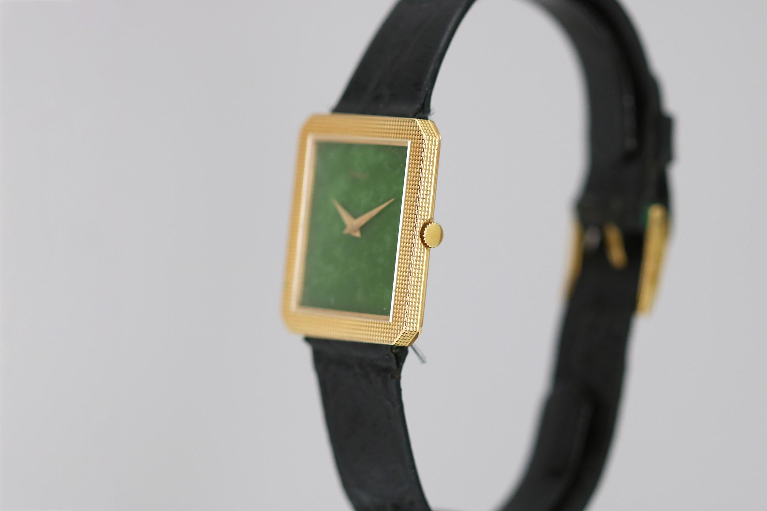 Piaget wristwatch with a rectangle ribbed 18k yellow gold case, green jade dial, manual wind movement and is on a skin black strap with Piaget 18k yellow gold tang buckle. 25x27mm circa 1970s