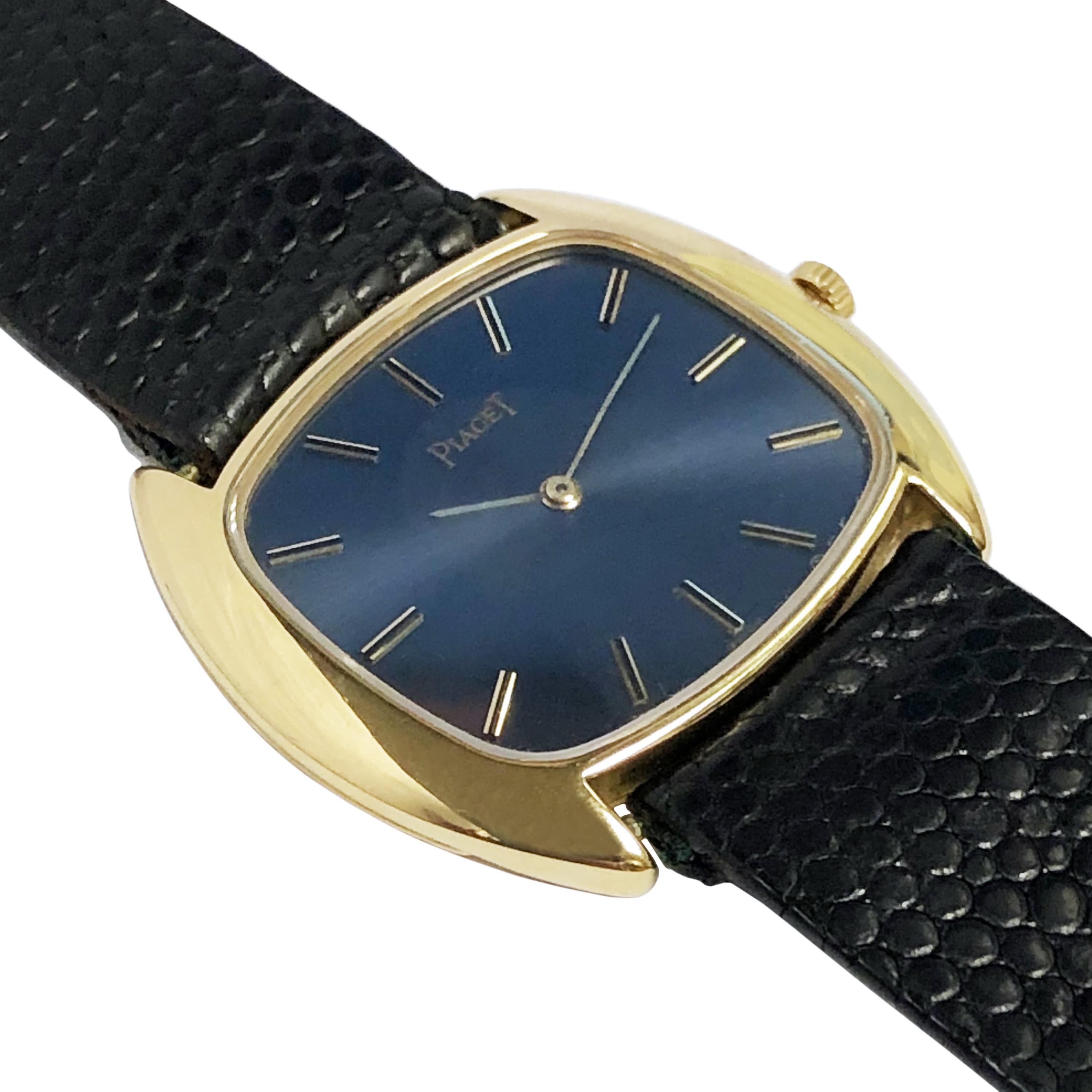 Circa 1970s Piaget Wrist Watch,  31 X 27 MM Cushion shape 18k Yellow Gold 2 piece case. 17 jewel mechanical, Manual wind movement, Navy Blue Satin dial with raised Gold markers. New Black Lizard strap with original Piaget 18k Gold buckle. Recently