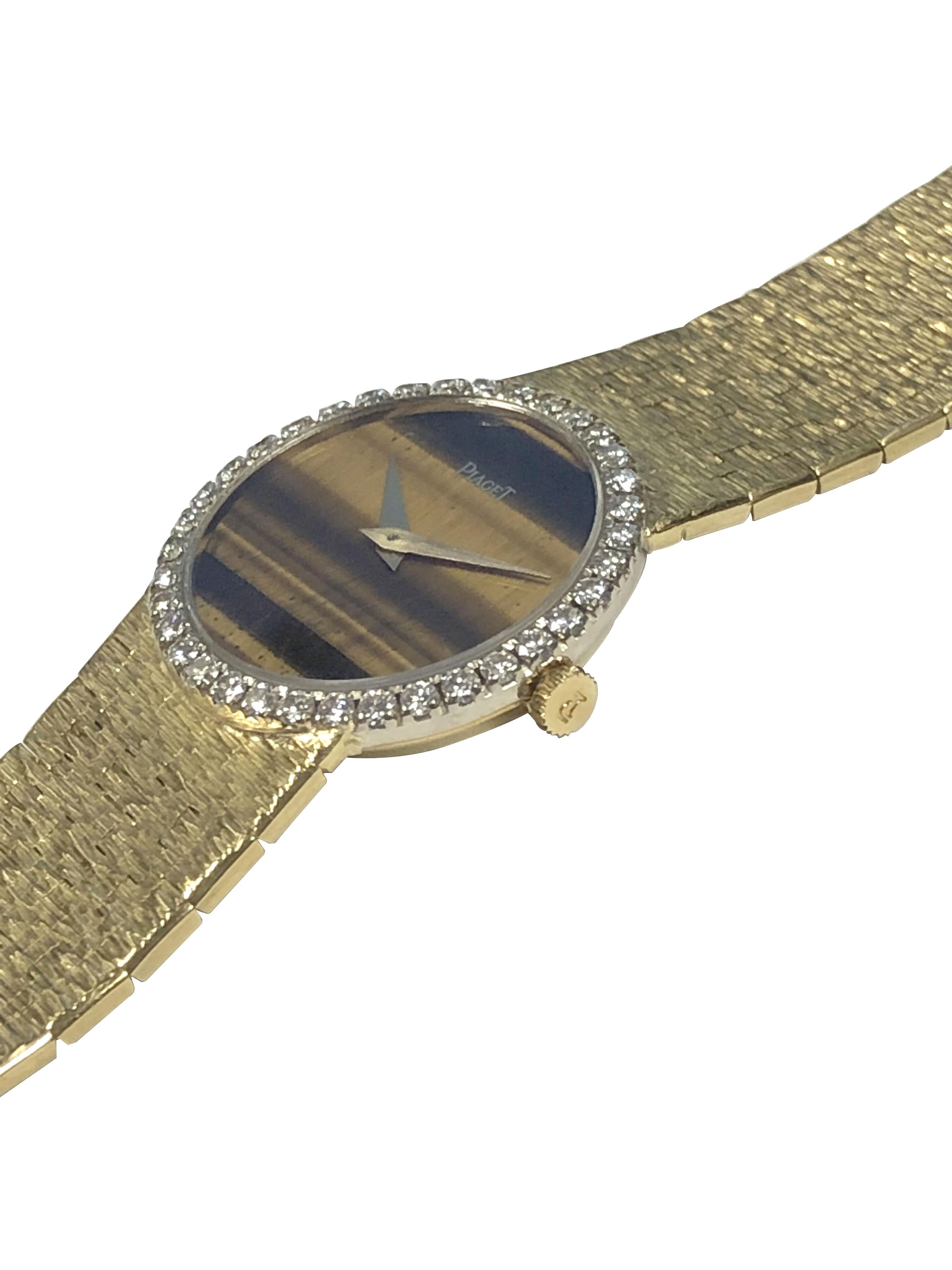 Circa 1980 Piaget Ladies Wrist Watch, 24 M.M. 2 piece 18K Yellow Gold case with White Gold bezel containing Fine White Round Brilliant cut Diamonds totaling 1 Carat. 17 Jewel Mechanical, Manual wind movement, Tigers Eye Dial and Gold Hands. 5/8 inch