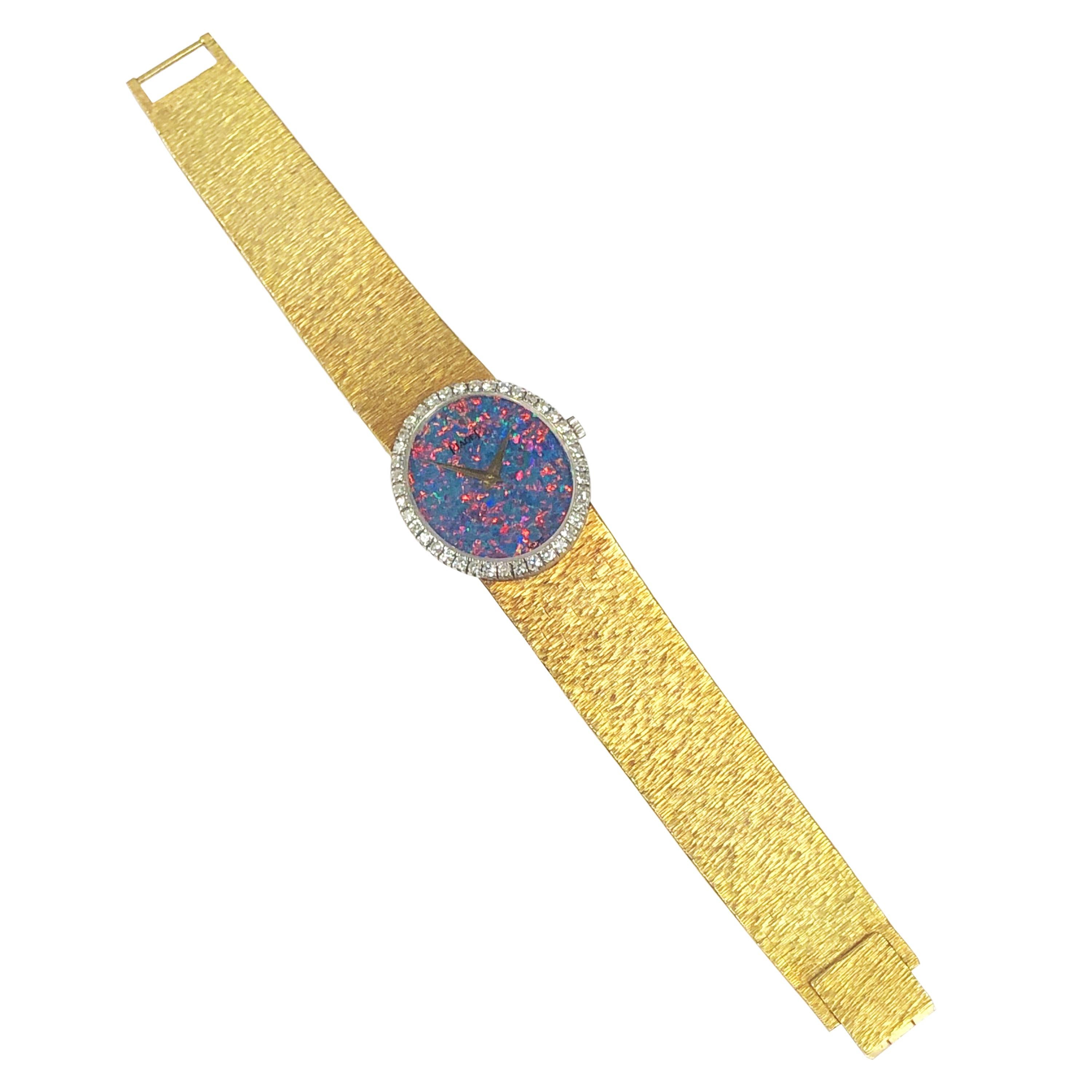 Circa 1980 Piaget Ladies Wrist watch, 27 X 24 MM 18K yellow Gold 2 Piece Oval case. Piaget Factory Diamond bezel of Round Brilliant cut Diamonds totaling 1 carat. Firey Opal dial with deep rich colors of reds, blues and greens. 17 jewel mechanical,