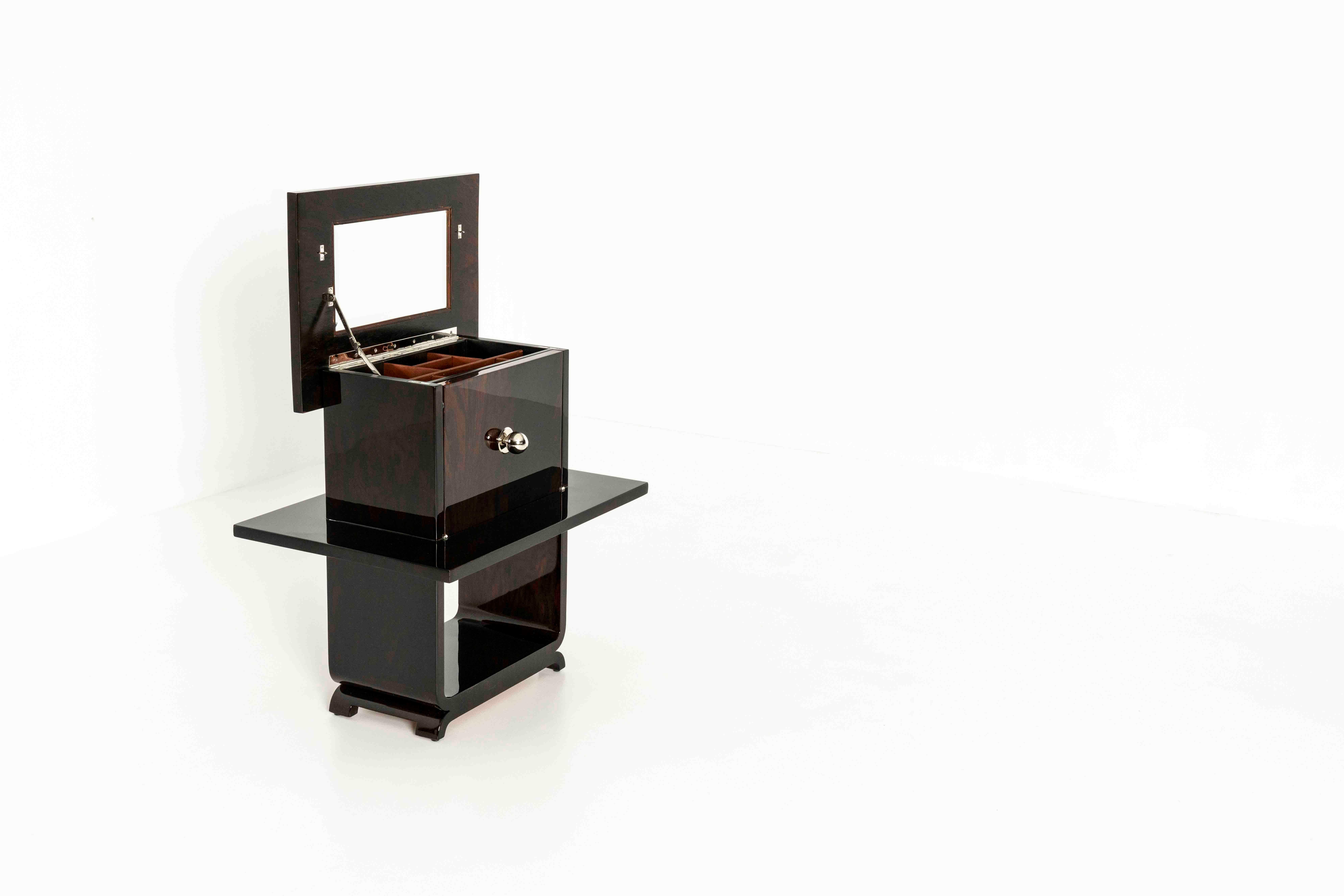 A beautiful piano lacquered bedside table or vanity cabinet. This piece has some nice surprises to it. The top opens leading to a mirror and a box for jewelry. The front panel covers two drawers. Where the back panel has a 'fake knob' for