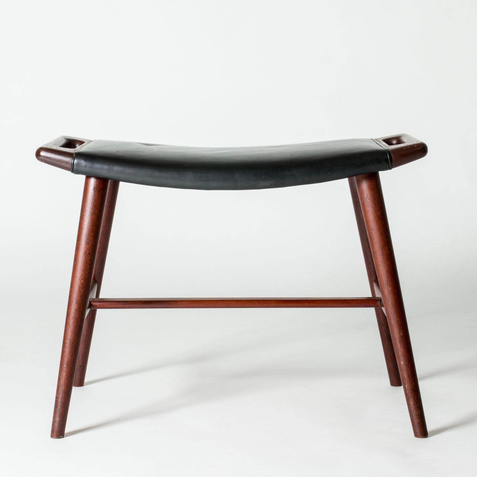 Rare piano stool by Hans J. Wegner, made from teak with original black leather upholstery. Beautiful sculpted handles on the sides of the seat.