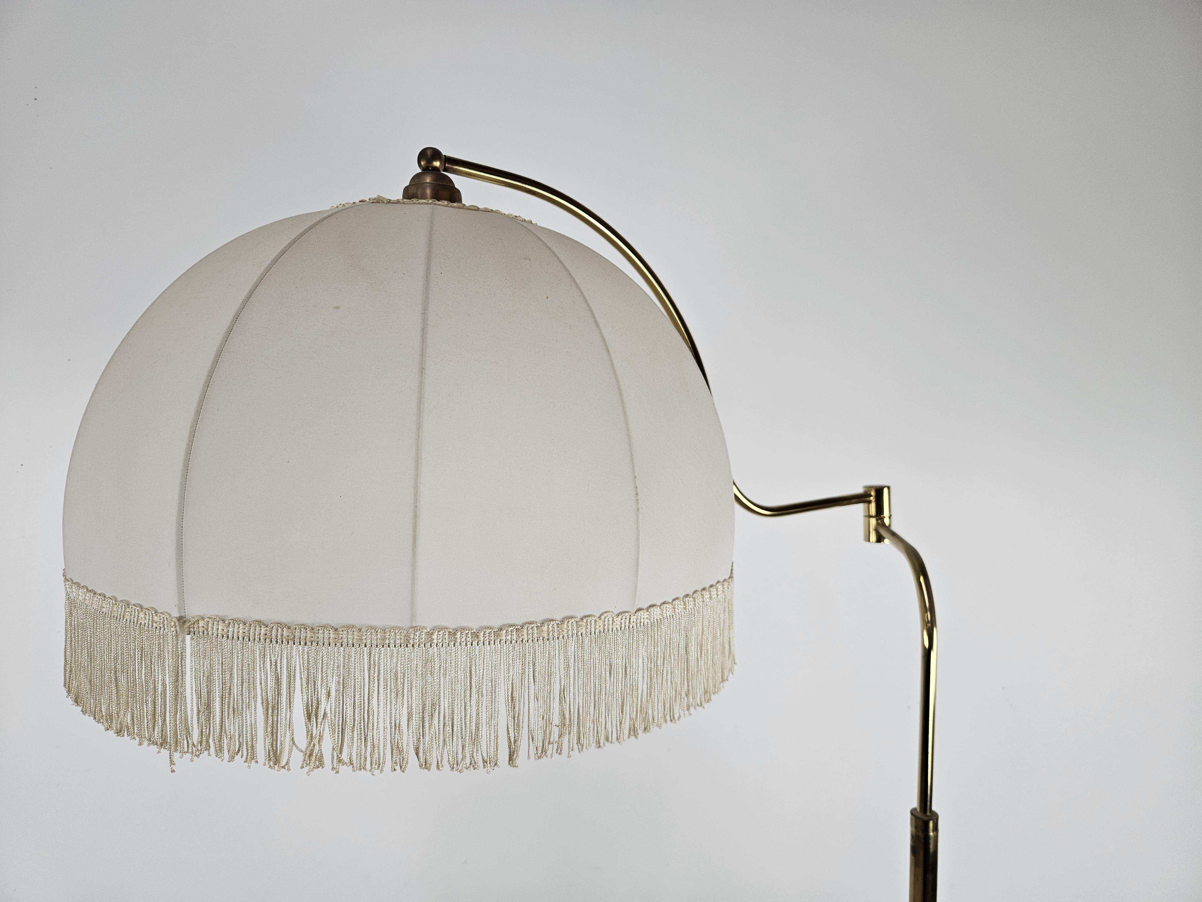 Lampadaire en métal doré avec bras réglable en largeur et en profondeur, parfait pour une utilisation comme lampe de lecture dans un salon ou une salle d'attente.

Abat-jour en tissu.

Signes normaux d'usure dus à l'âge et à l'utilisation, en
