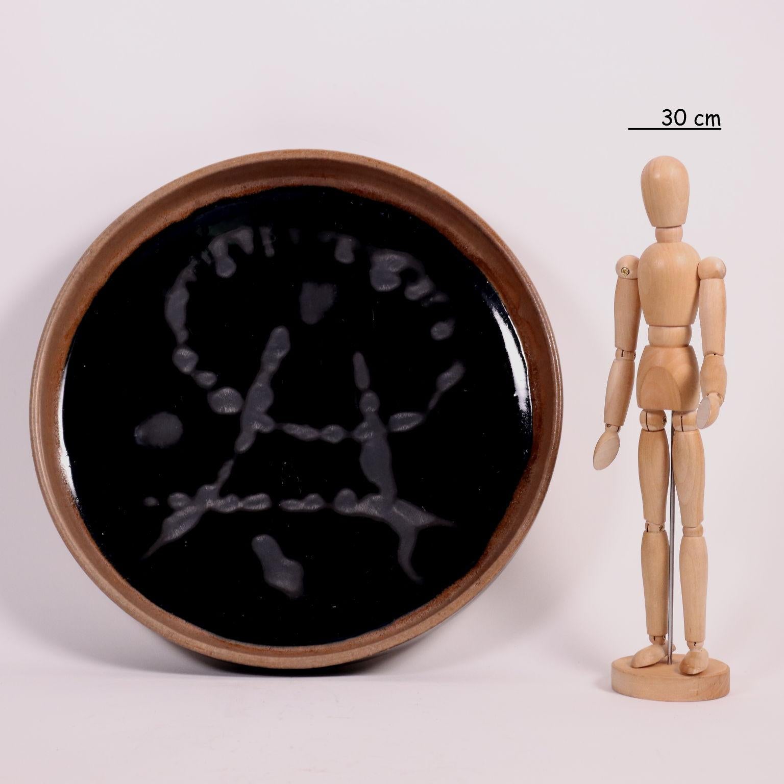 Plat en céramique polychrome. Signature de l'artiste sous la base. 