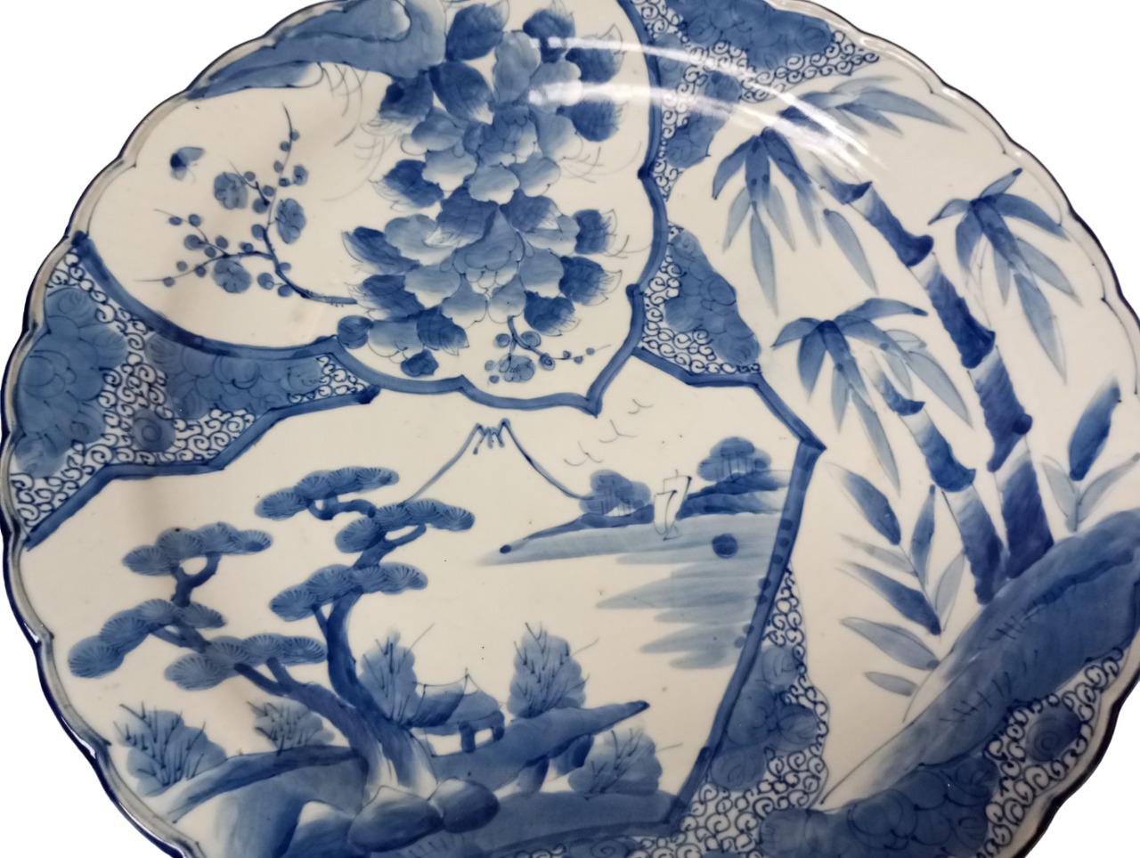 This large Japanese plate, with a diameter of about 47 cm, is made of hand-painted porcelain. The design is dominated by the white colors of the background, with blue and light blue designs typical of traditional oriental ceramics, giving the dish a