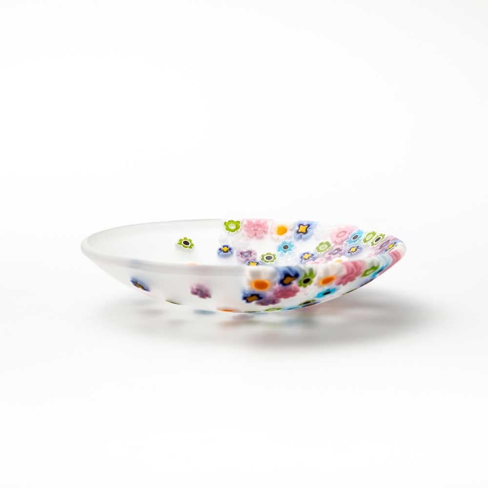 La primavera, con il suo vento leggero, sparge le murrine sul piatto come se fosse una danza di fiori. Progettato da Paolo Cappello, questo piatto utilizza la tecnica del “vetro murrino millefiori”, che unisce segmenti di bacchetta di vetro decorati