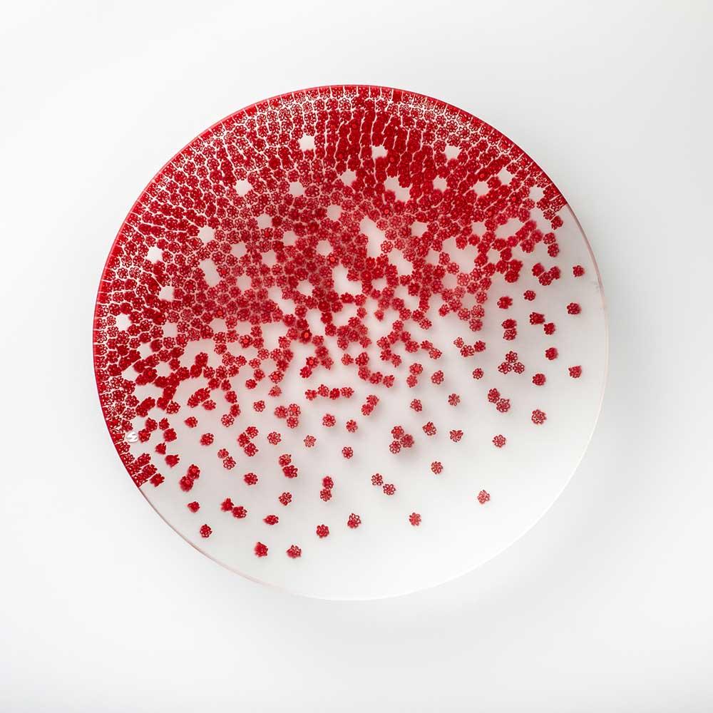 Le murrine che adornano il piatto sembrano danzare, come trascinate da un dolce vento di primavera. Creato da Paolo Cappello, questo piatto è realizzato con la tecnica del “vetro murrino millefiori”, che fonde insieme frammenti di bacchetta di