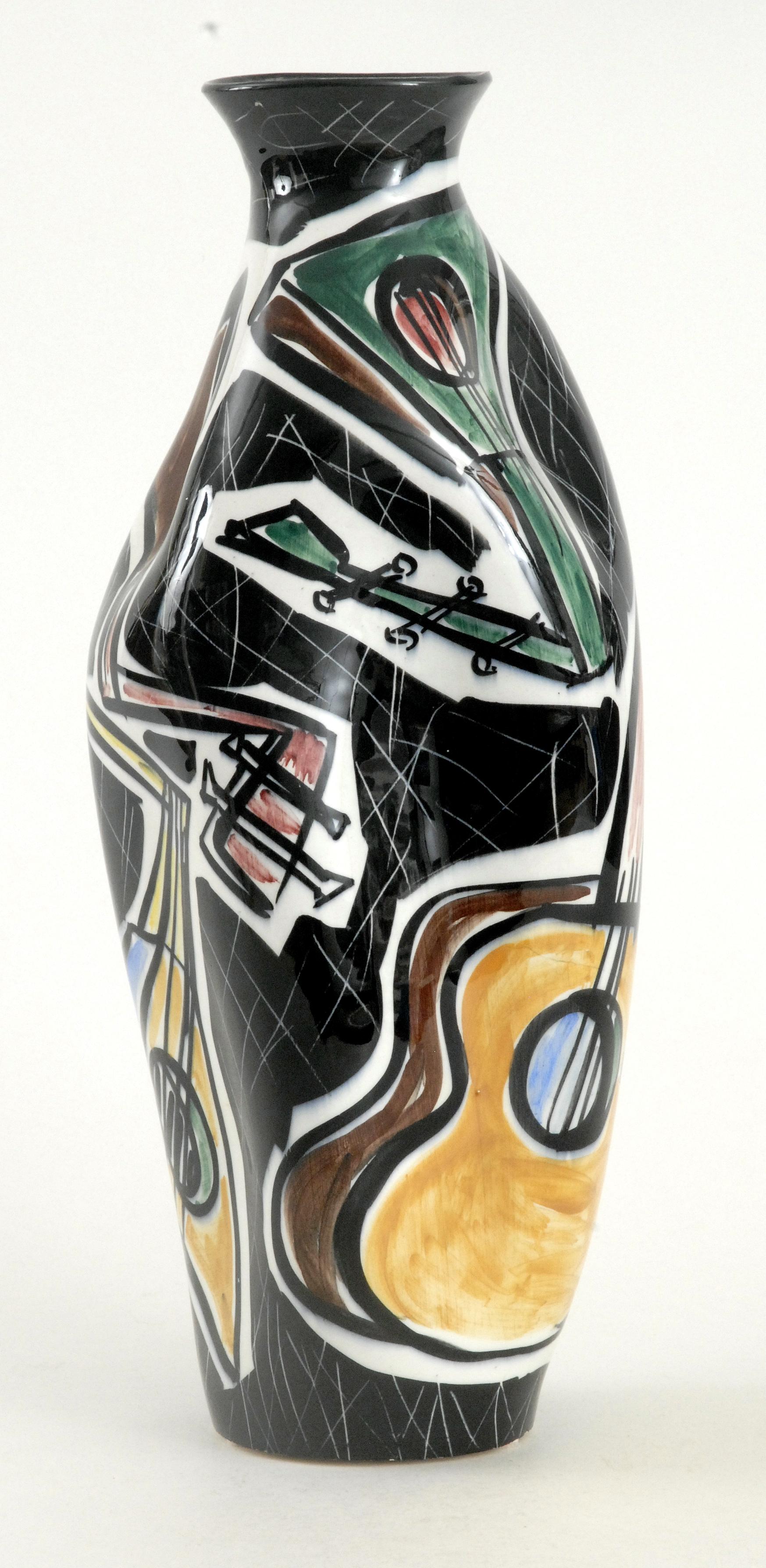 A large highly decorated vase with pushed in sides painted with guitars in various colors and shapes in white cartouches on an overall black background. Stylistically influenced by the Cubist Movement painters, Picasso and Braque et al.
Stamped