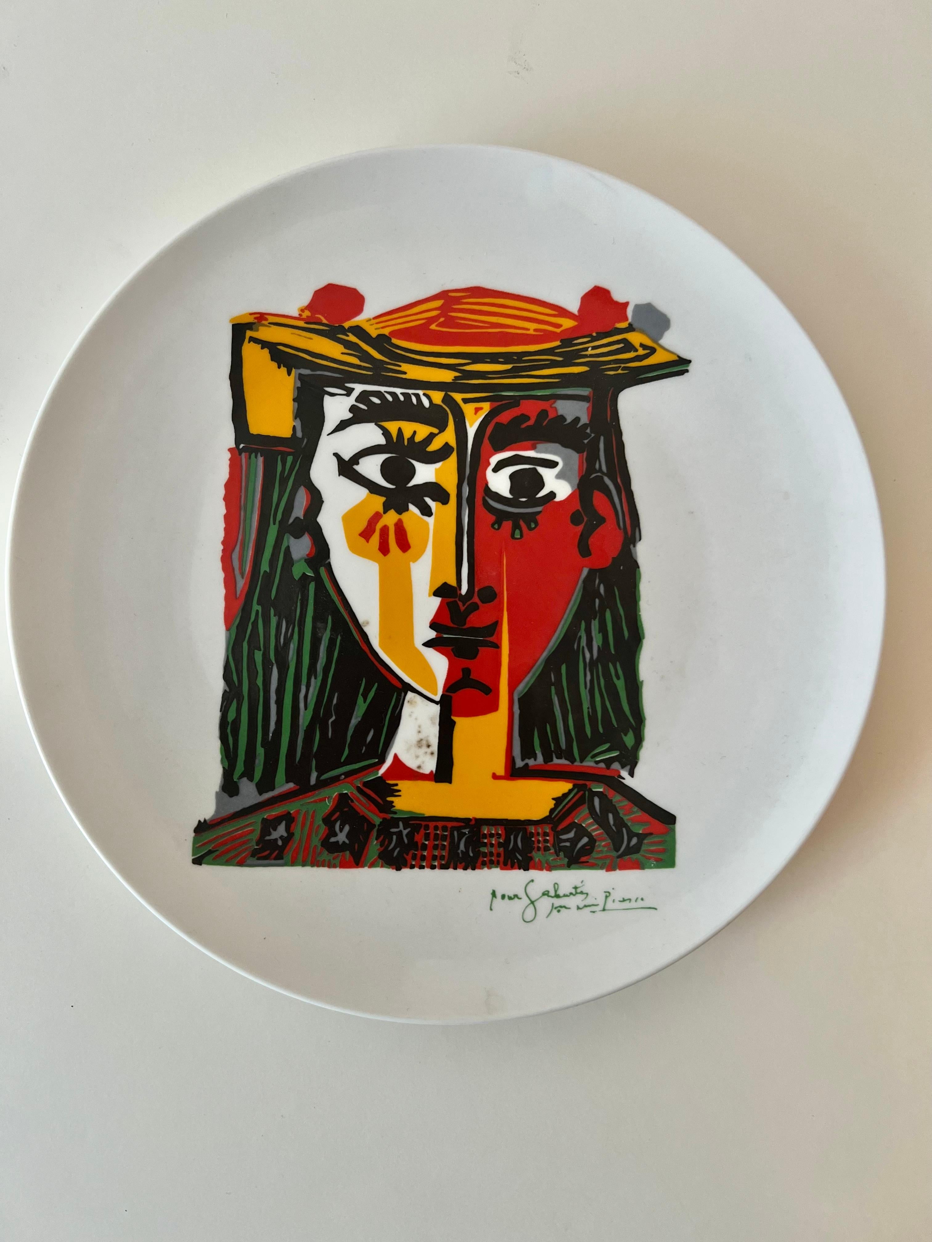 A Painted plate with the Picasso image. The plate would be a nice decorative piece to a cocktail table or grouping on a table or wall. the vivid colors are very modern and relative. Porcelain with no chips or cracks.