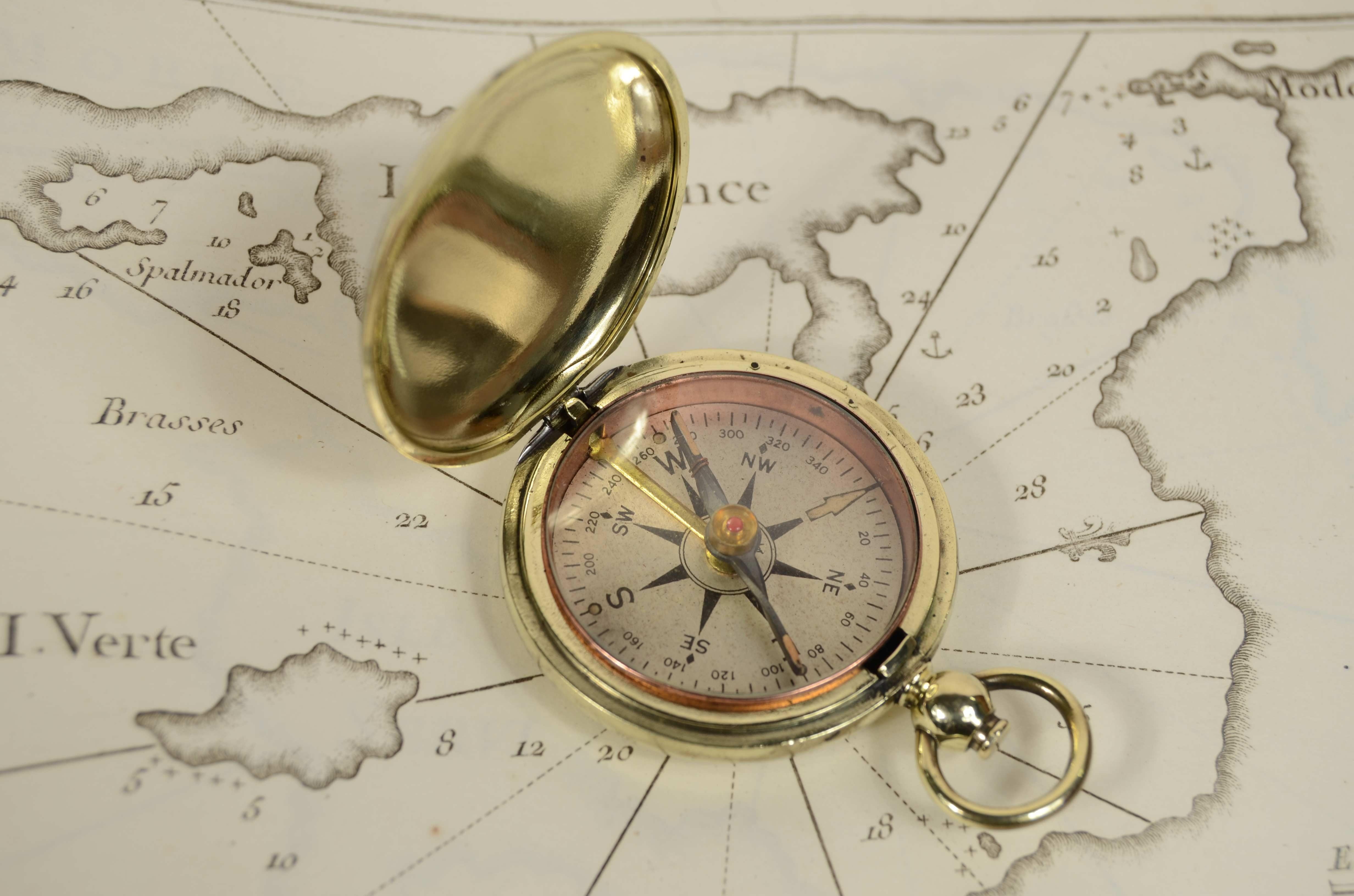 Small brass travel compass, issued to the U.S. Army during World War I, shaped like an onion pocket watch, an instrument consisting of a magnetized needle free to rotate in a horizontal plane marking the direction of magnetic north. Signed Taylor.