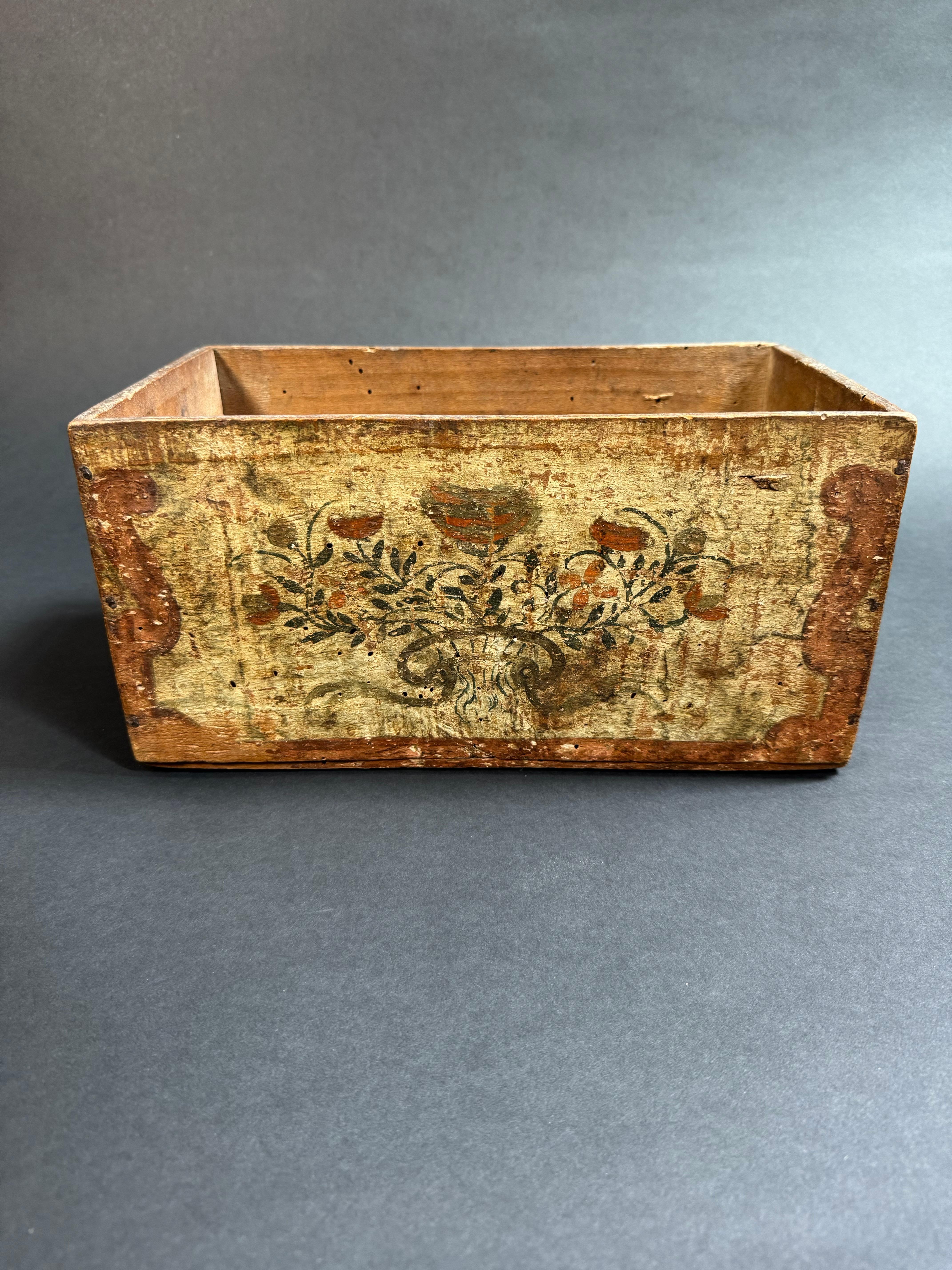 Piccola cassetta in legno dipinta pugliese del XVIII secolo. Le decorazioni presentano motivi floreali e vegetali stilizzati nei toni del rosso, verde e giallo, tipici dell'arte popolare e contadina. In passato queste tipologie di oggetti venivano