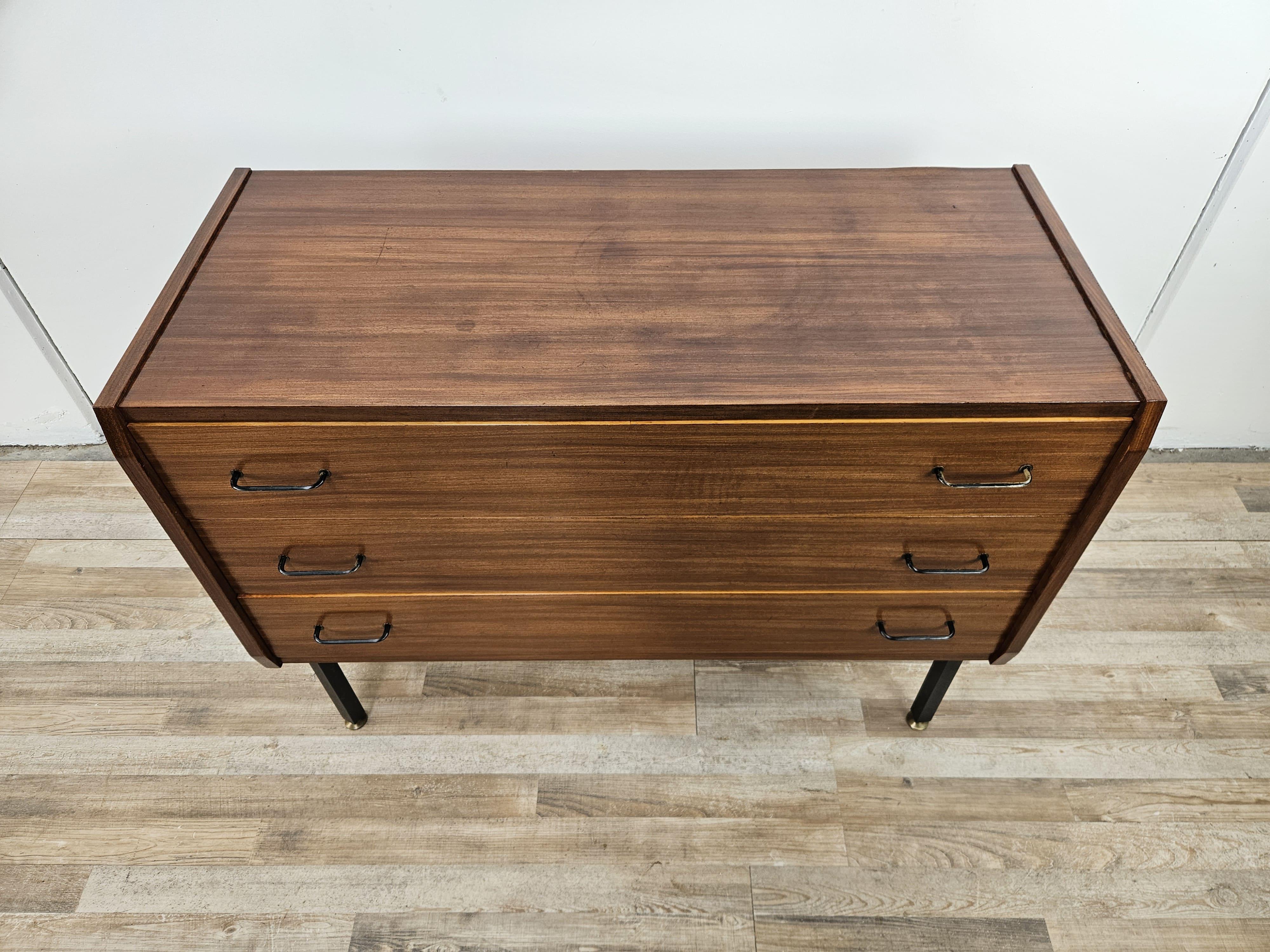 Piccola cassettiera in legno di teak con tre ampi cassetti e maniglie in ferro, produzione anni '70 design scandinavo e regolabile in altezza grazie ai piedini.

Presenta alcuni segni d'usura come da foto, in particolare dentro i cassetti.