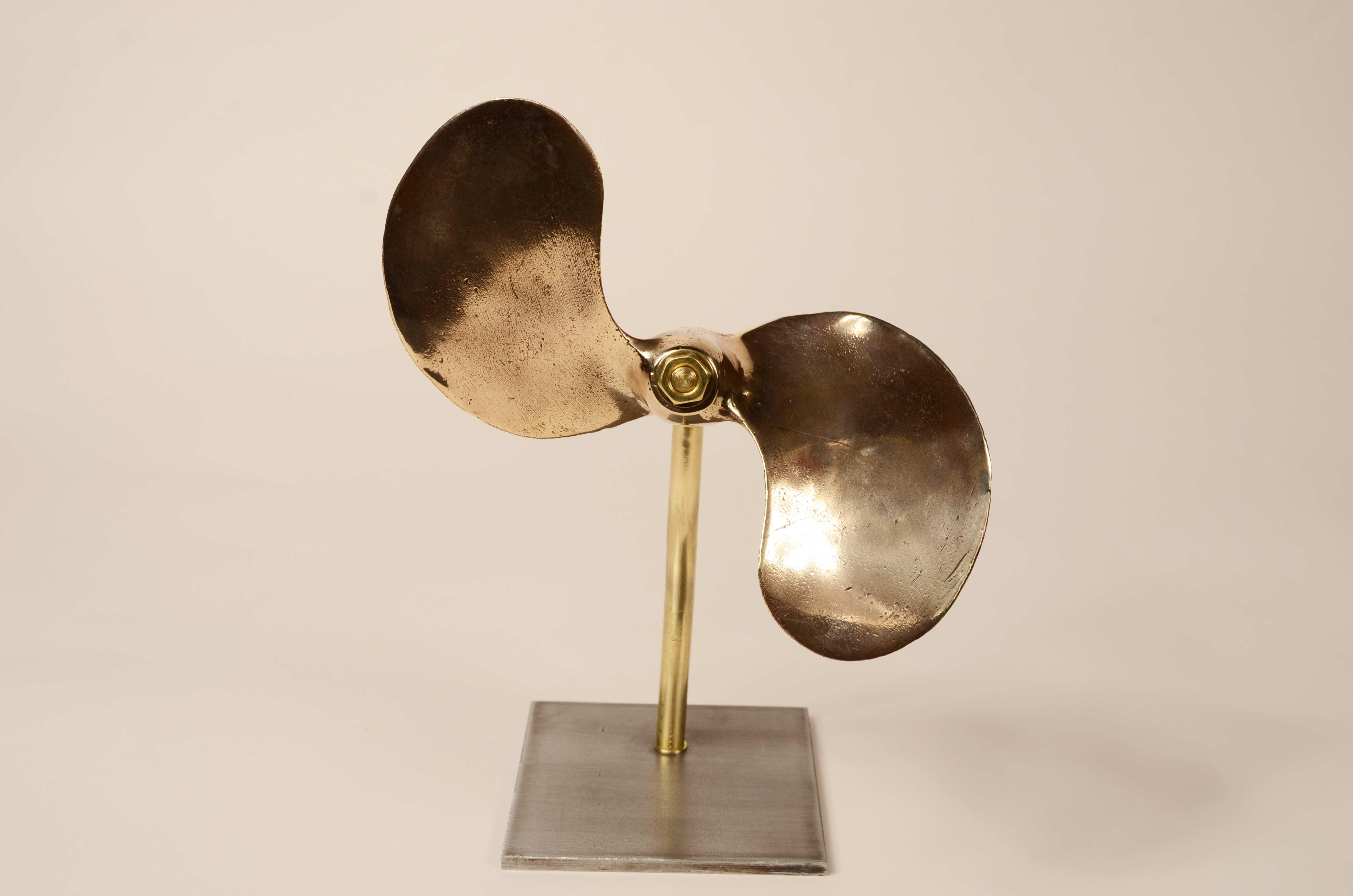 Small propeller  bronze bipala, British manufacture of the 1930s. 
Width 19 cm - 7.5 inch, height 8.5 cm - 3.4 inch, depth 4.5 cm - 1.8 inch. The propeller is mounted on a custom-made iron and brass base. Good  state. 
The last photo is the gift