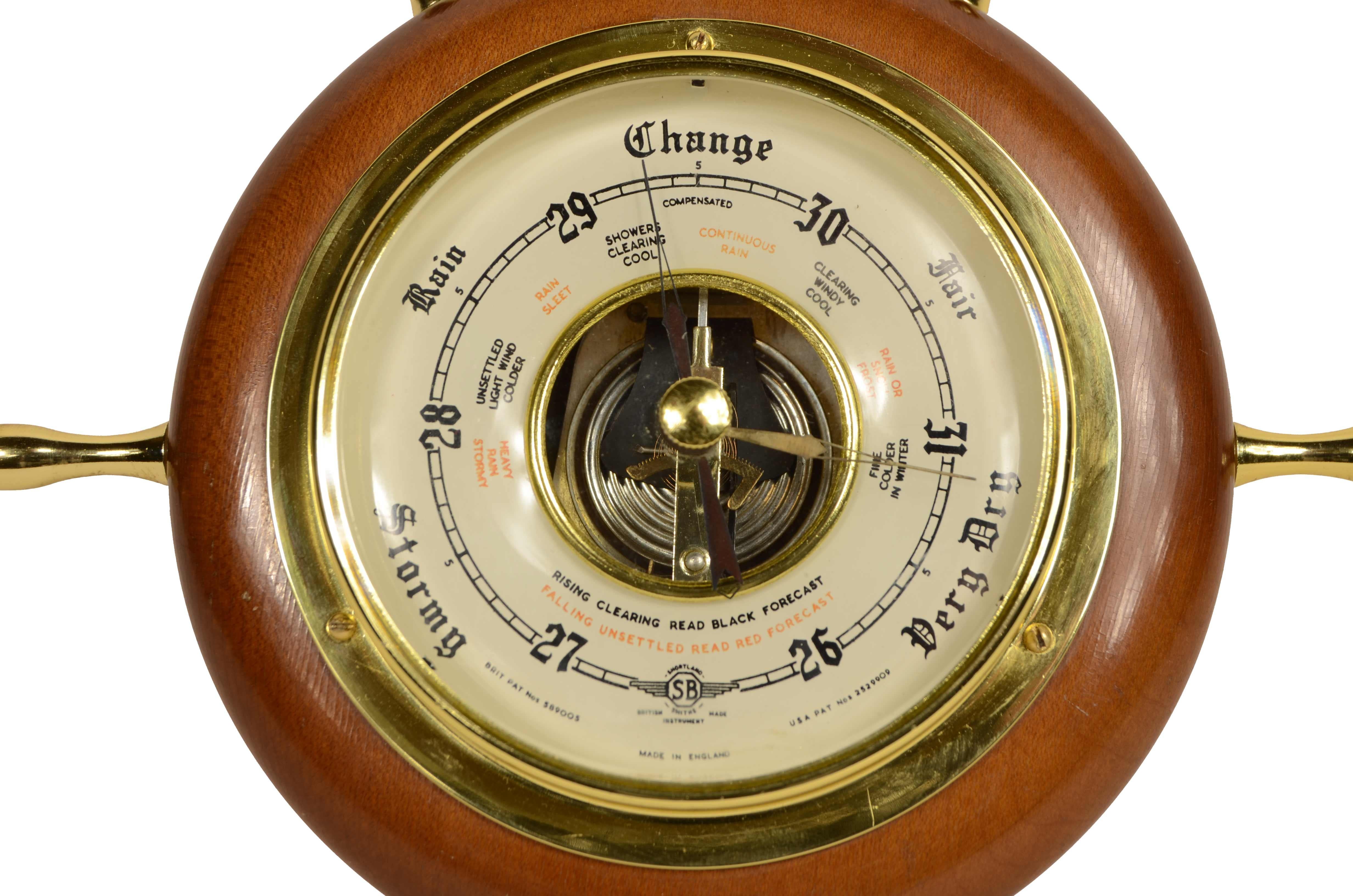 Petit baromètre anéroïde mural en bois et en laiton en forme de gouvernail à six chevilles. Signé  Instrument SB Smiths de fabrication britannique des années 1950. Il s'agit d'un instrument dont l'organe sensible à la pression est une boîte