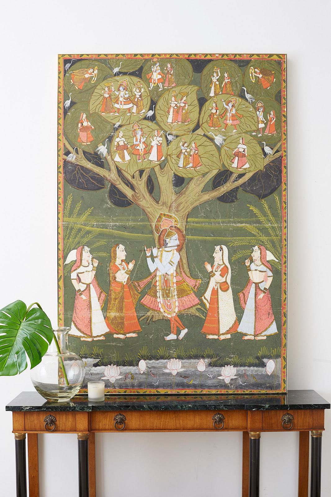 Colorful Pichhwai painting of Hindu deity Krishna depicted under the tree of life. He is playing a basuri flute for gopis of milkmaids. In the tree he is depicted six more times in various scenes with gopis and white cranes watching. Vibrant colors
