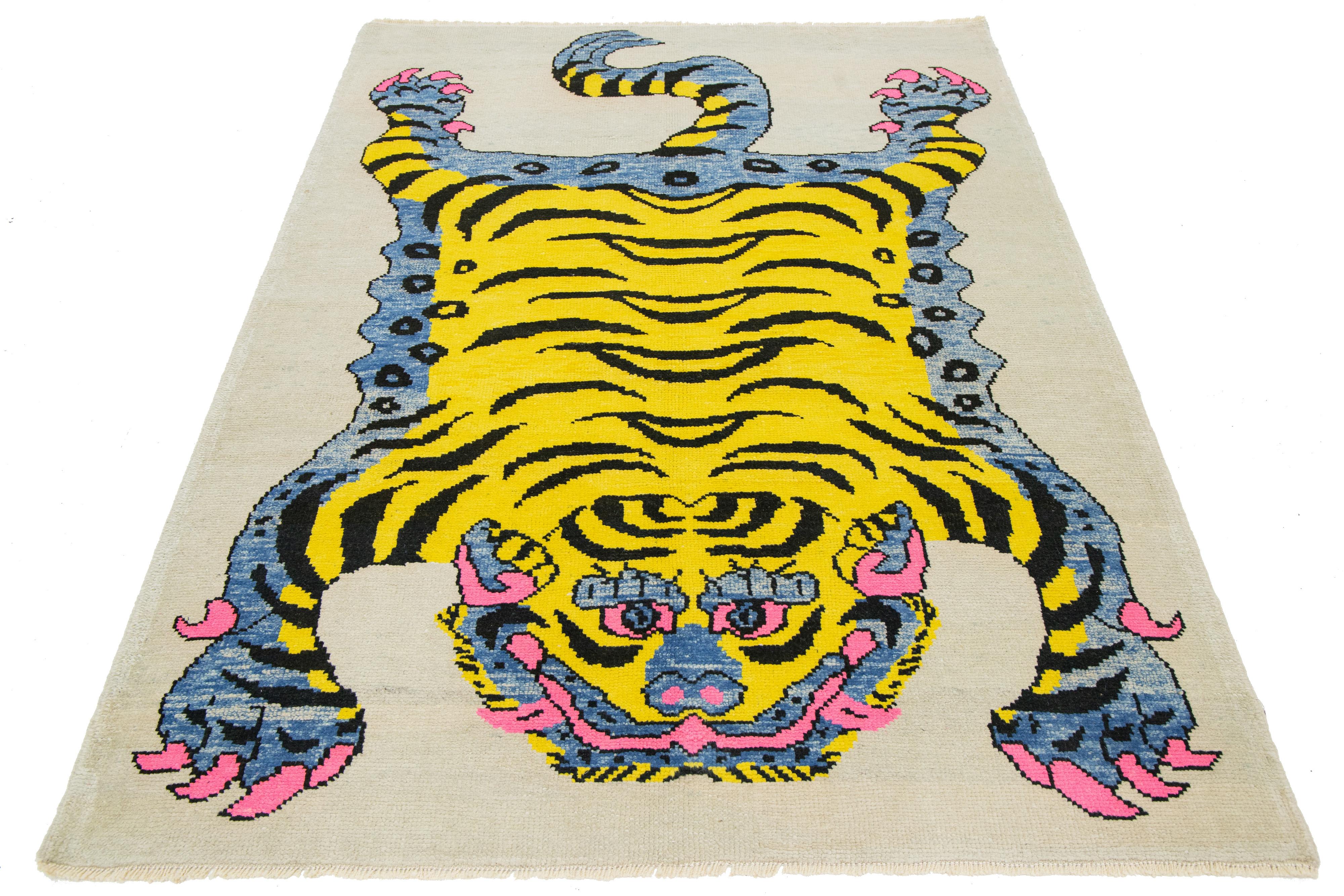 This Turkish Art Deco wool rug boasts a striking beige backdrop with black, yellow, gray, and pink accents and a captivating pictorial representation of a tiger.

This rug measures 5'5