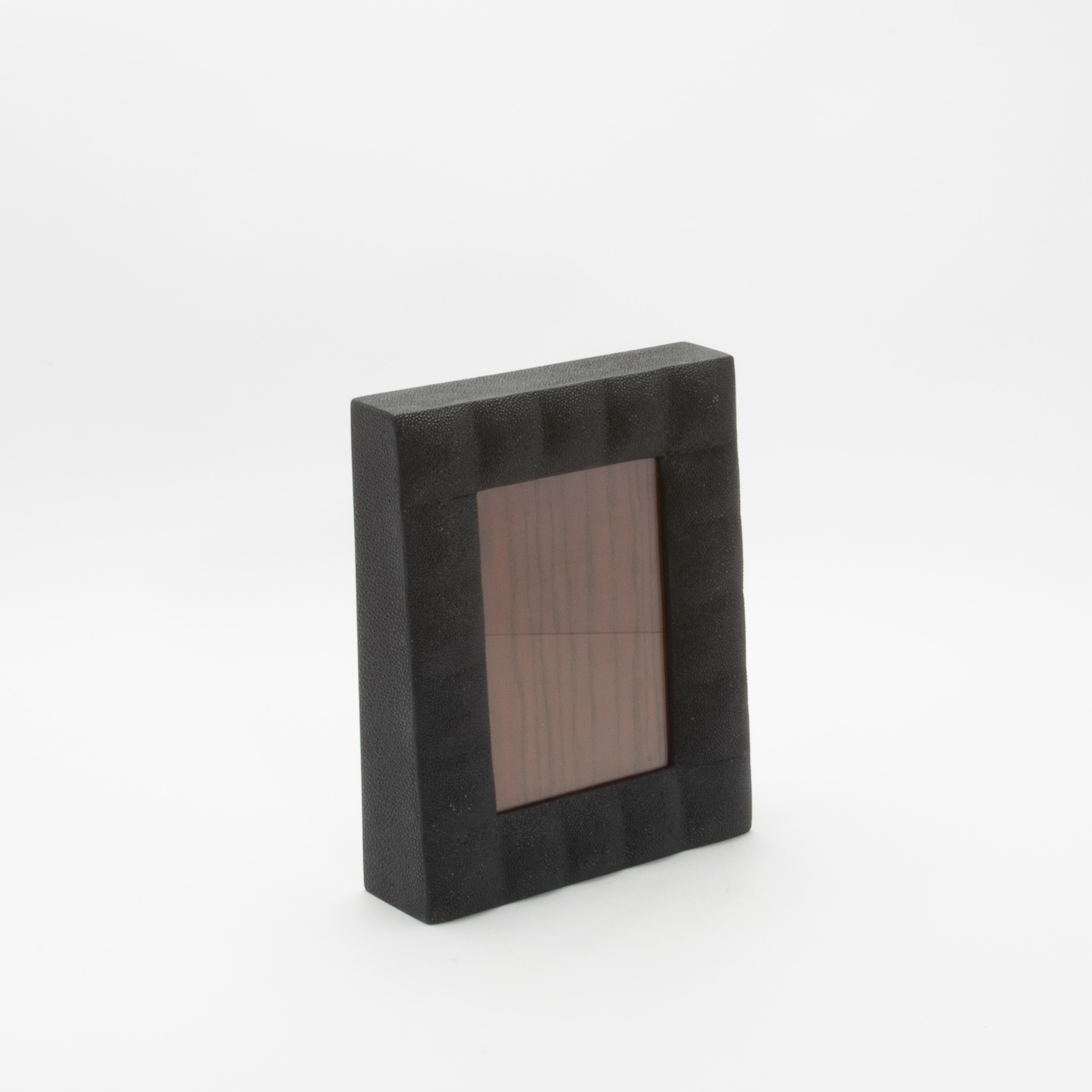 Este lujoso marco de R & Y Augousti está fabricado en su característico acolchado de piel de zapa negra, que destila elegancia atemporal y refinamiento moderno. La textura táctil del acabado shagreen contrasta maravillosamente con la ventana de