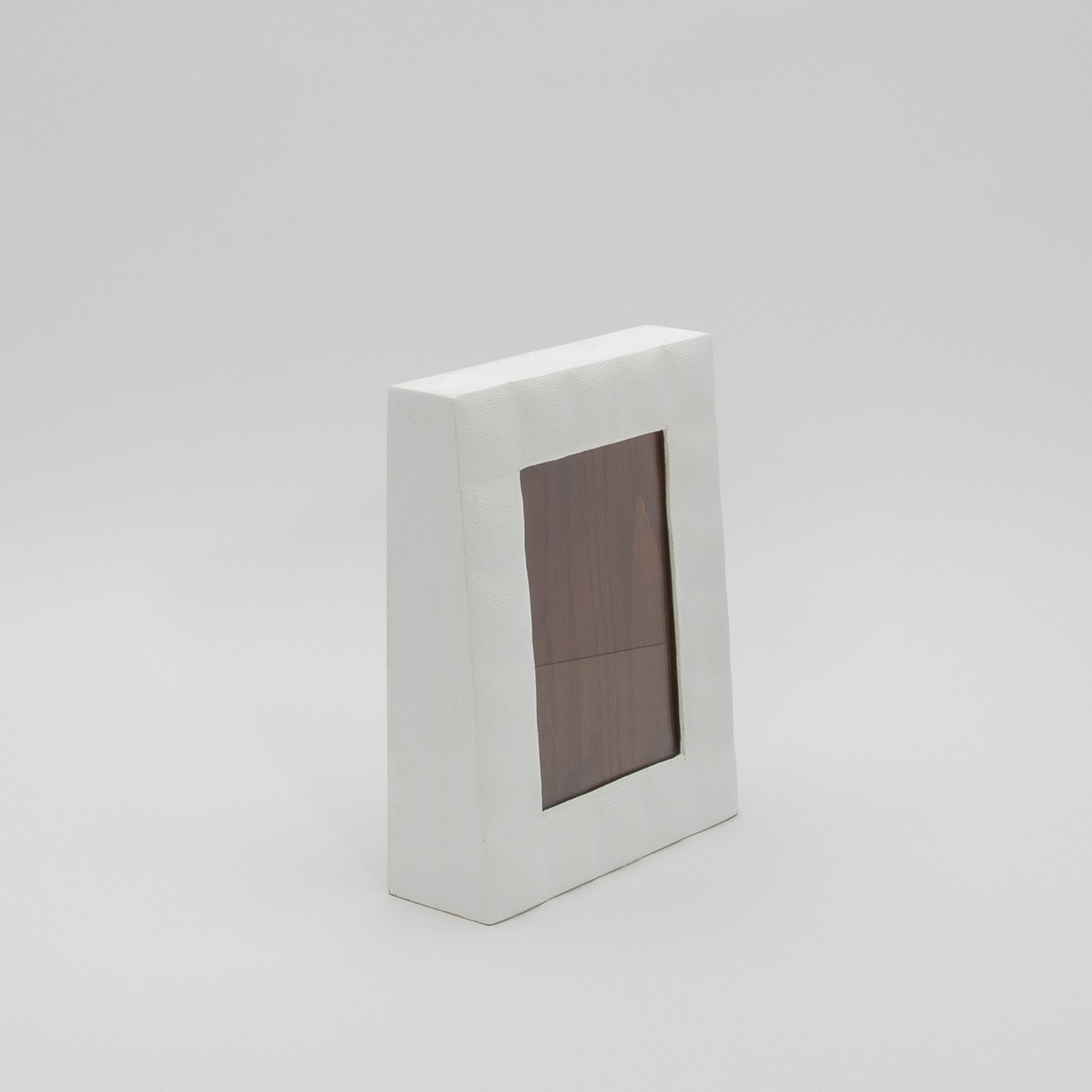 Este lujoso marco de R & Y Augousti está fabricado en su característico acolchado de piel de zapa blanca, que destila elegancia atemporal y refinamiento moderno. La textura táctil del acabado shagreen contrasta maravillosamente con la ventana de