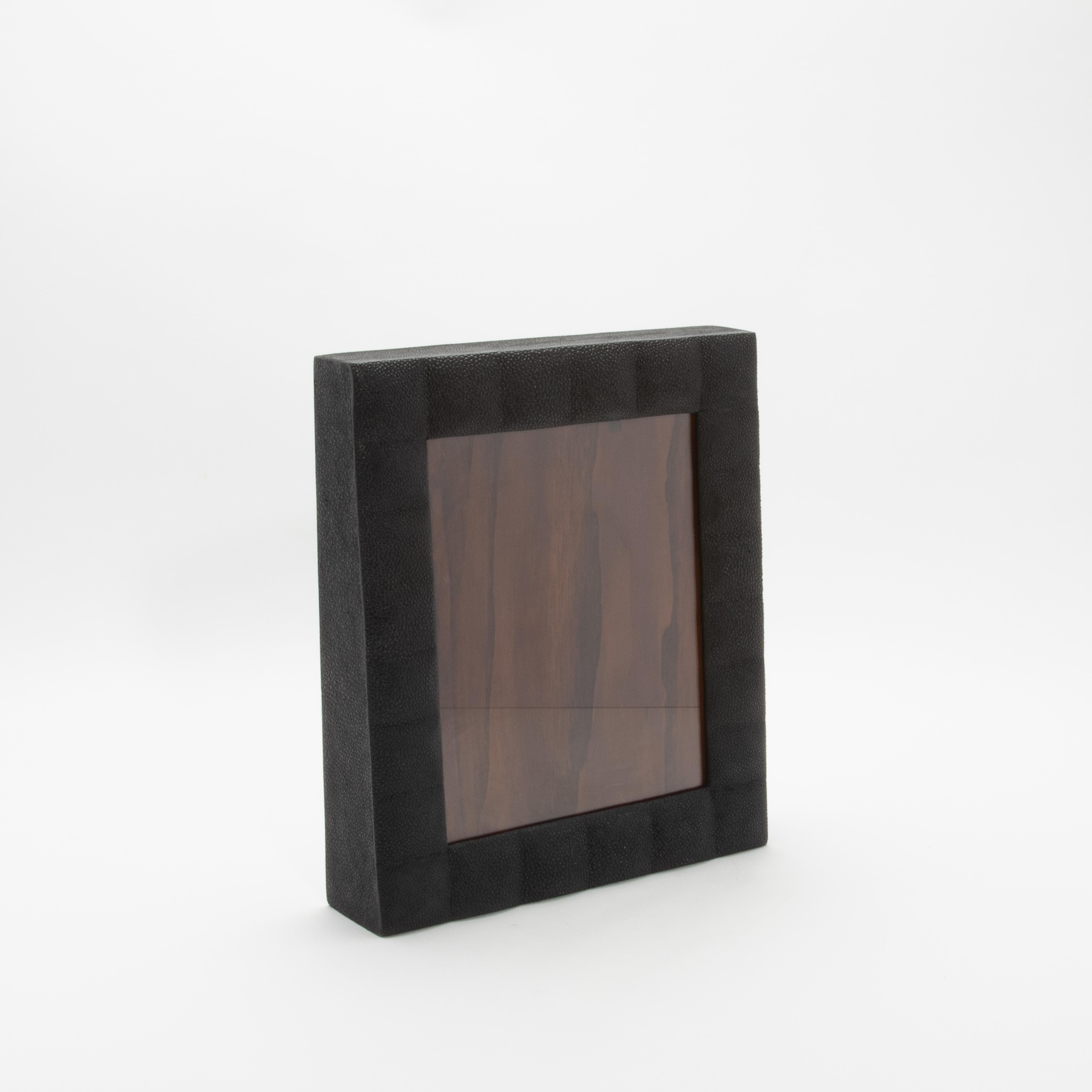 Este lujoso marco de R & Y Augousti está fabricado en su característico acolchado de piel de zapa negra, que destila elegancia atemporal y refinamiento moderno. La textura táctil del acabado shagreen contrasta maravillosamente con la ventana de