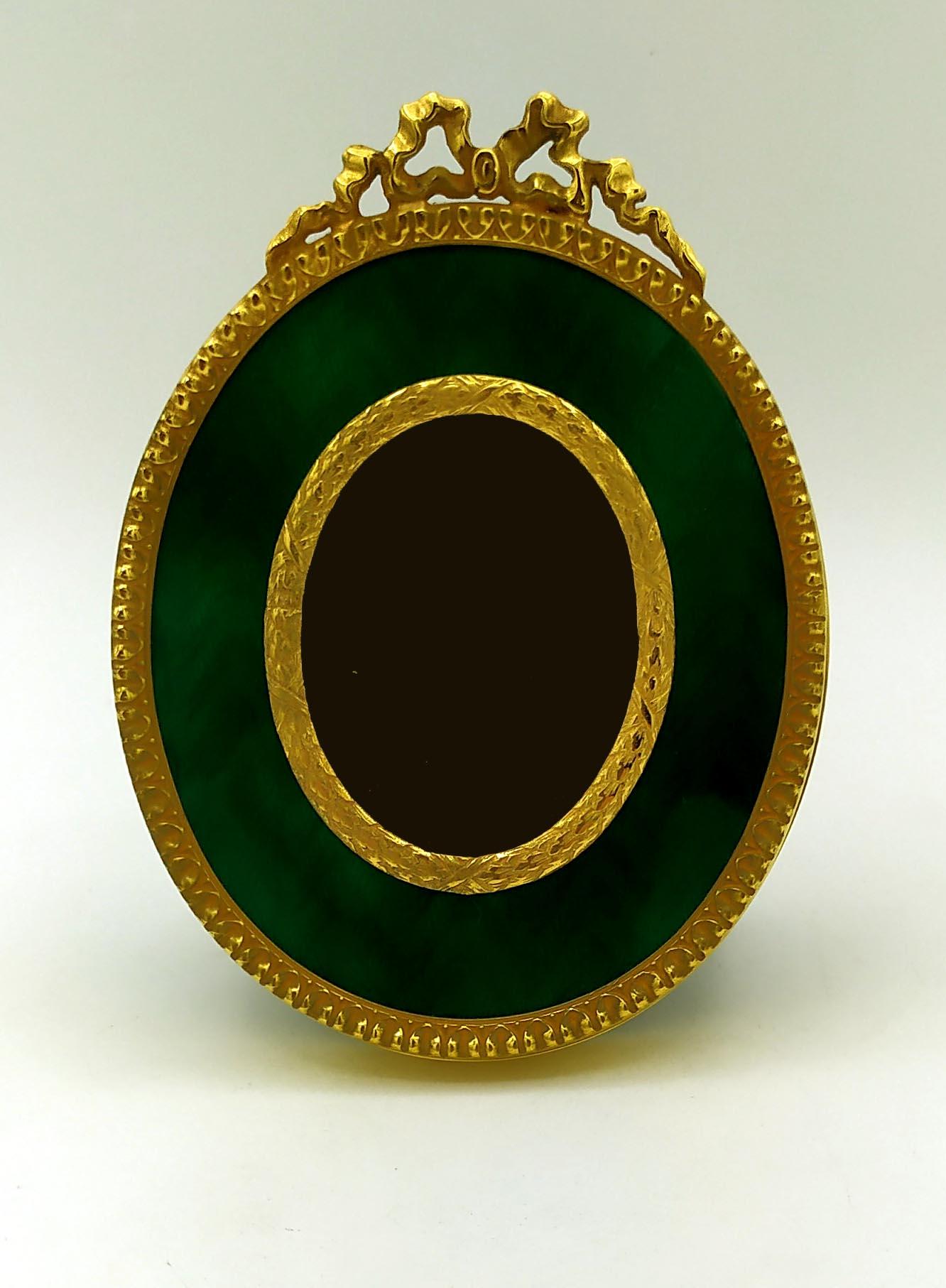 Marco de fotos ovalado de plata de ley 925/1000 dorada con esmalte al fuego verde esmeralda translúcido sobre guilloché y con adornos de estilo Imperio francés Napoleón III. Tamaño exterior cm. 8,8 x 12 internas cm. 4 x 5.3. Peso gr. 135. Diseñada