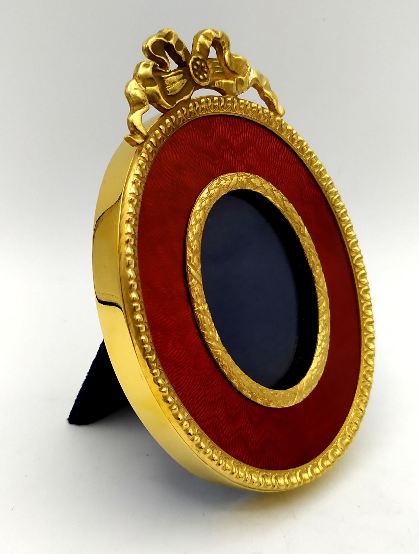 Marco de fotos ovalado de plata de ley 925/1000 dorada con esmalte al fuego rojo rubí translúcido sobre guilloché y con adornos de estilo Imperio francés Napoleón III. Tamaño exterior cm. 8,8 x 12 internas cm. 4 x 5.3. Peso gr. 135. Diseñada por