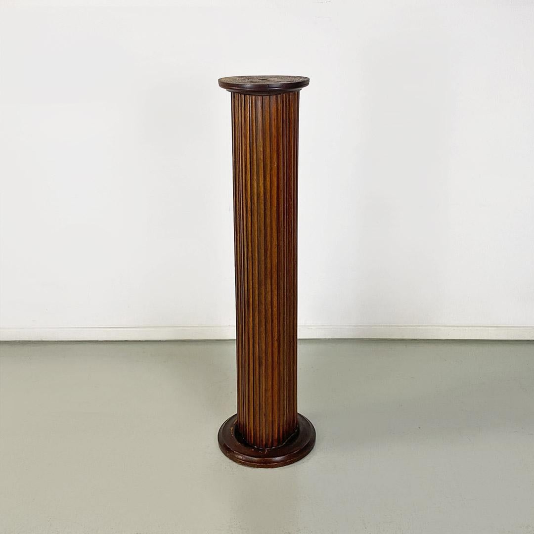 Pedestal or column display stand made of wood with finish the shaped relief, with repeated pattern, irregular cross-section and not round, although the support base and top are round in shape. The latter has a rough finish, with a small central