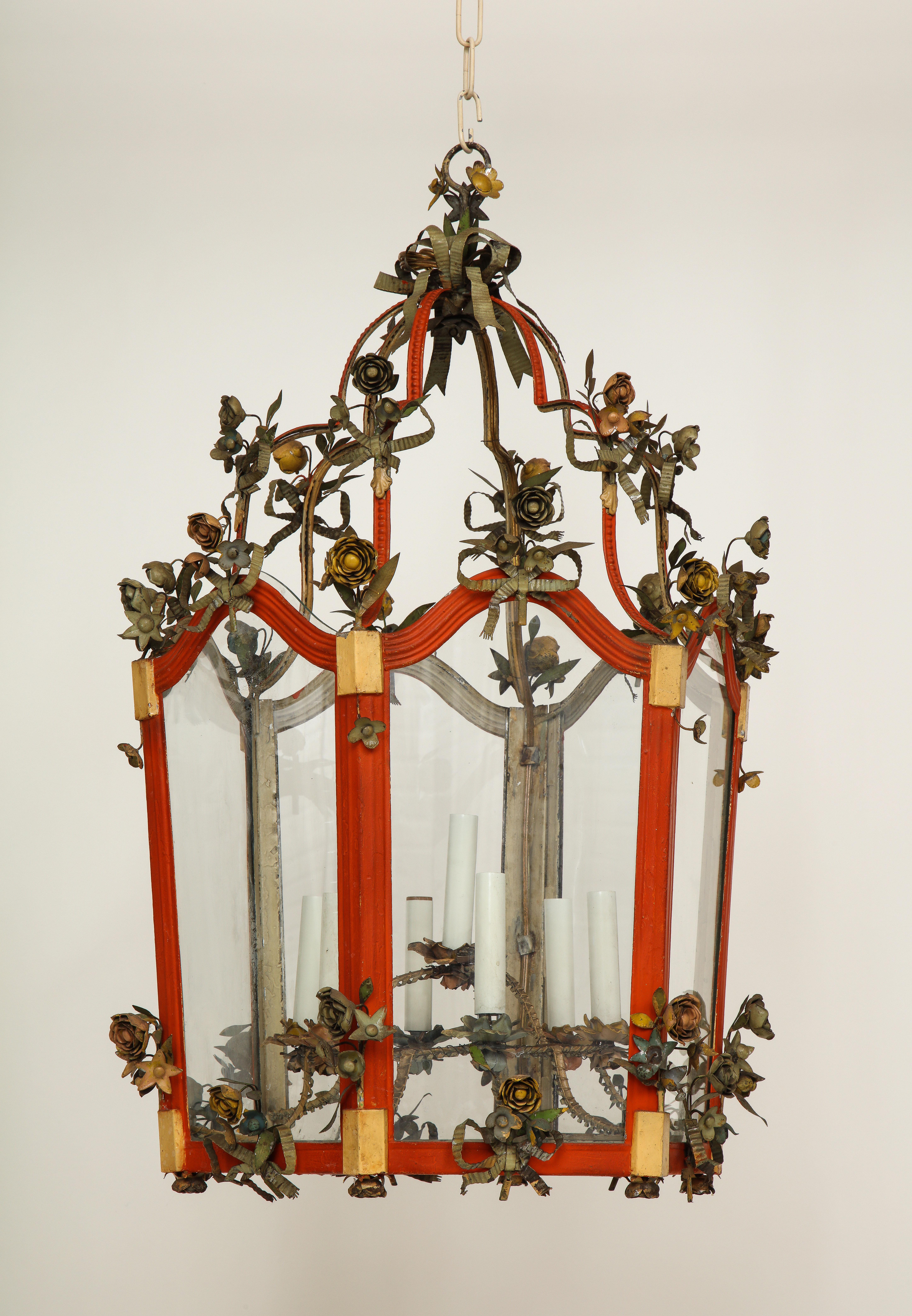 The orange-red frame with ochre yellow detailing and festooned with pale blue bow-tied ribbons and roses. Wire with four lights.