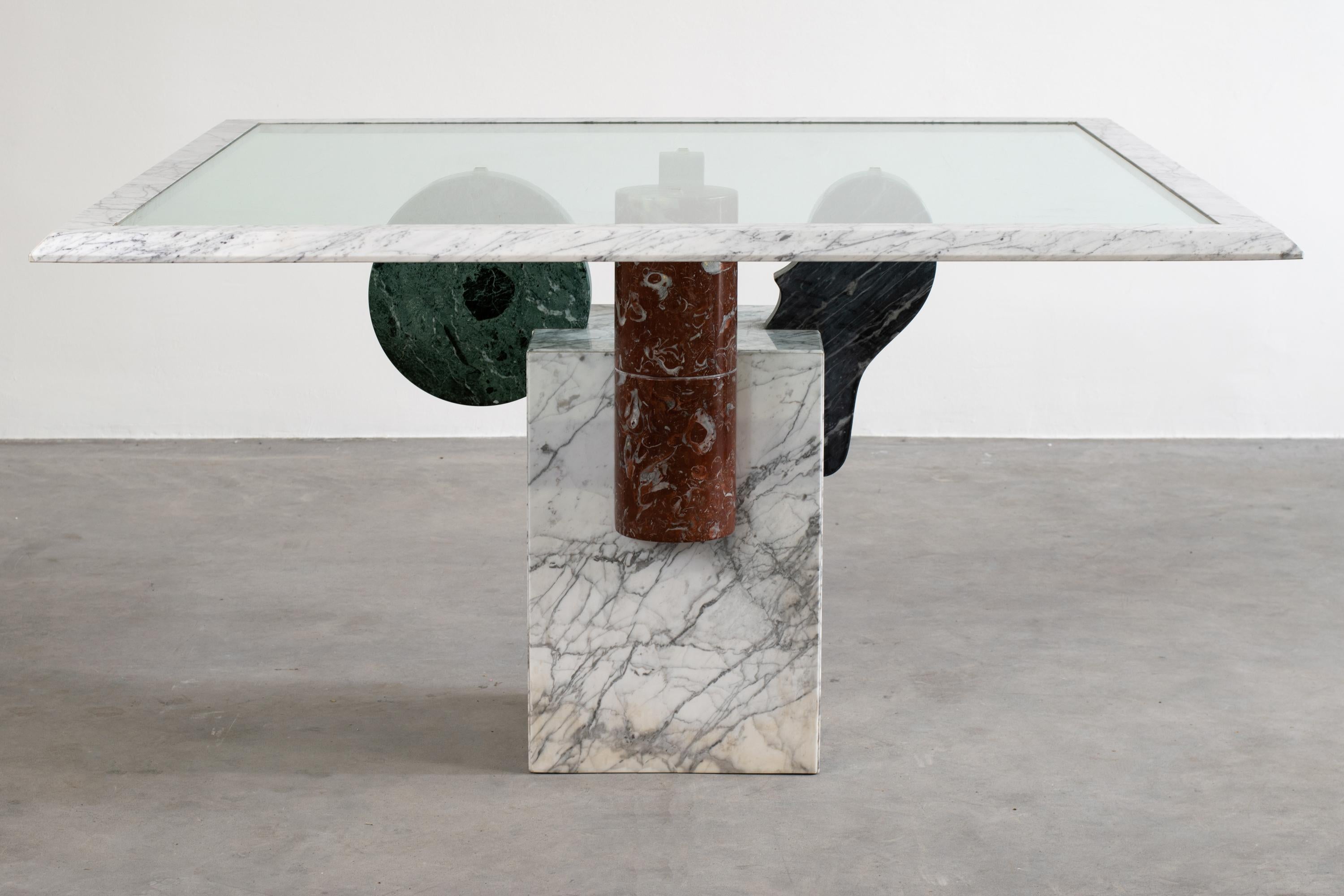 Square Brugiana table with a base in white Carrara marble and geometric elements in arabescato, green Alpi, sandstone, and red Levanto marble, glass on top with a white Carrara marble frame.
Brugiana table was designed by Pier Alessandro Giusti and