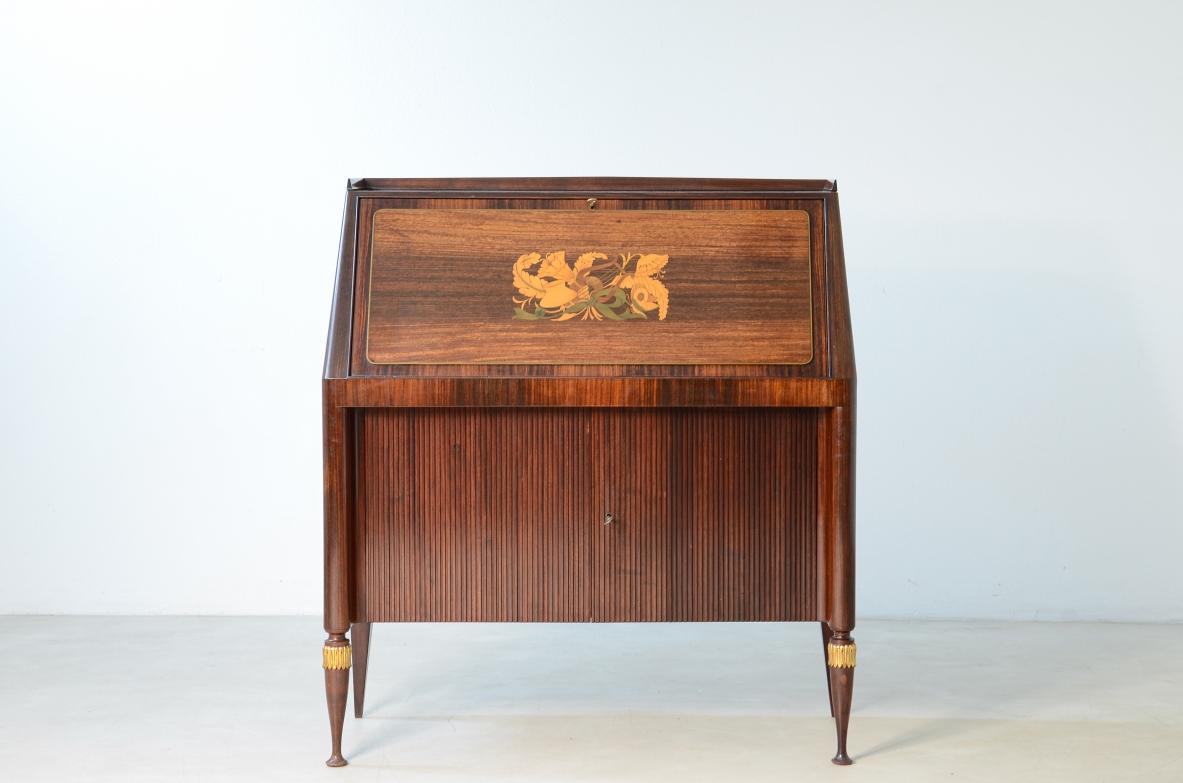 Pier Luigi Colli (1895-1968)

Straordinario mobile di alta qualità con un fronte a ribalta intarsiato con legni pregiati e ottone inciso su disegno di Giovanni Gariboldi. Eleganza, punte finemente tornite e decorate con foglia d'oro. Due porte curve