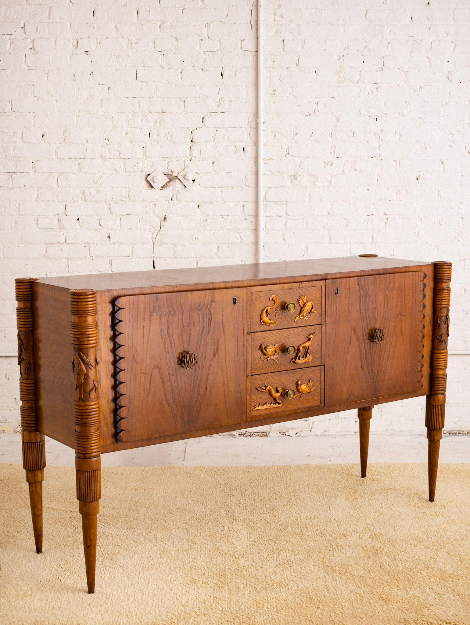 A mid century Italian sideboard / credenza by designer Pier Luigi Colli. Carved animal reliefs and spindle legs with Art Deco influences. Brass accents. Sourced outside of Milan, Italy.