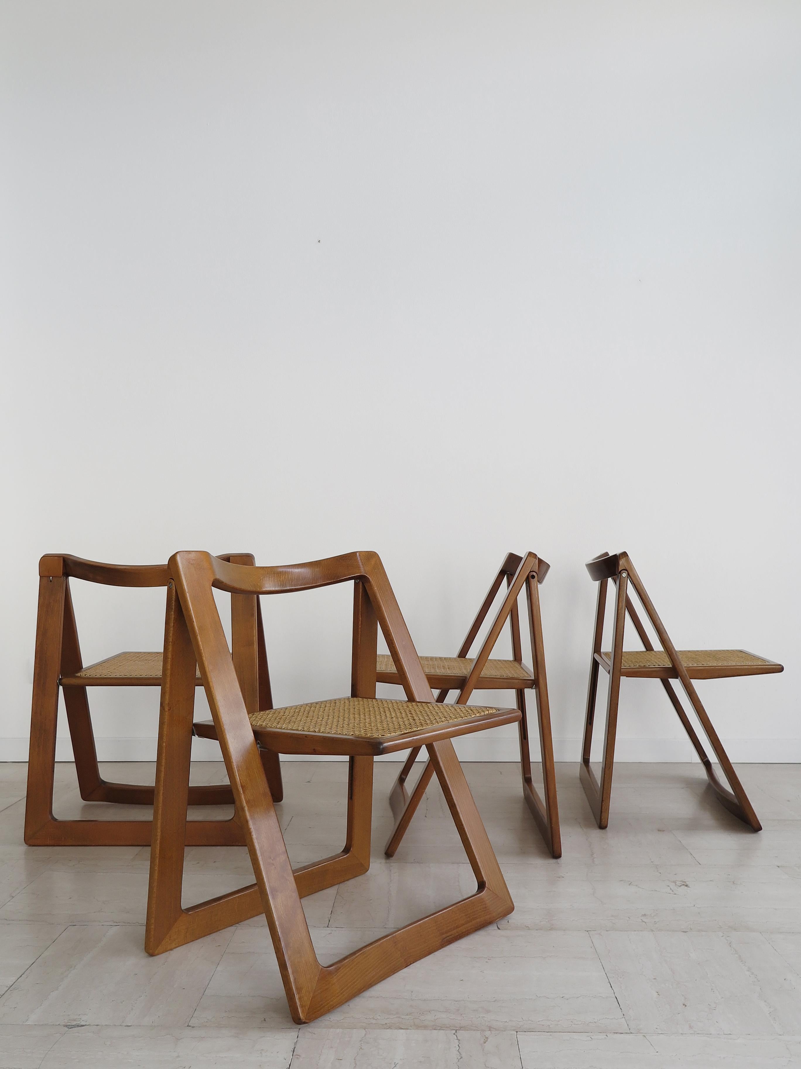 Set of four Italian Mid-Century Modern design folding dining chairs with tip-up seat model “Trieste” designed by Pierangela D’Aniello and Aldo Jacober and produced by Alberto Bazzini with seat in woven rattan cane and lacquered wood structure,