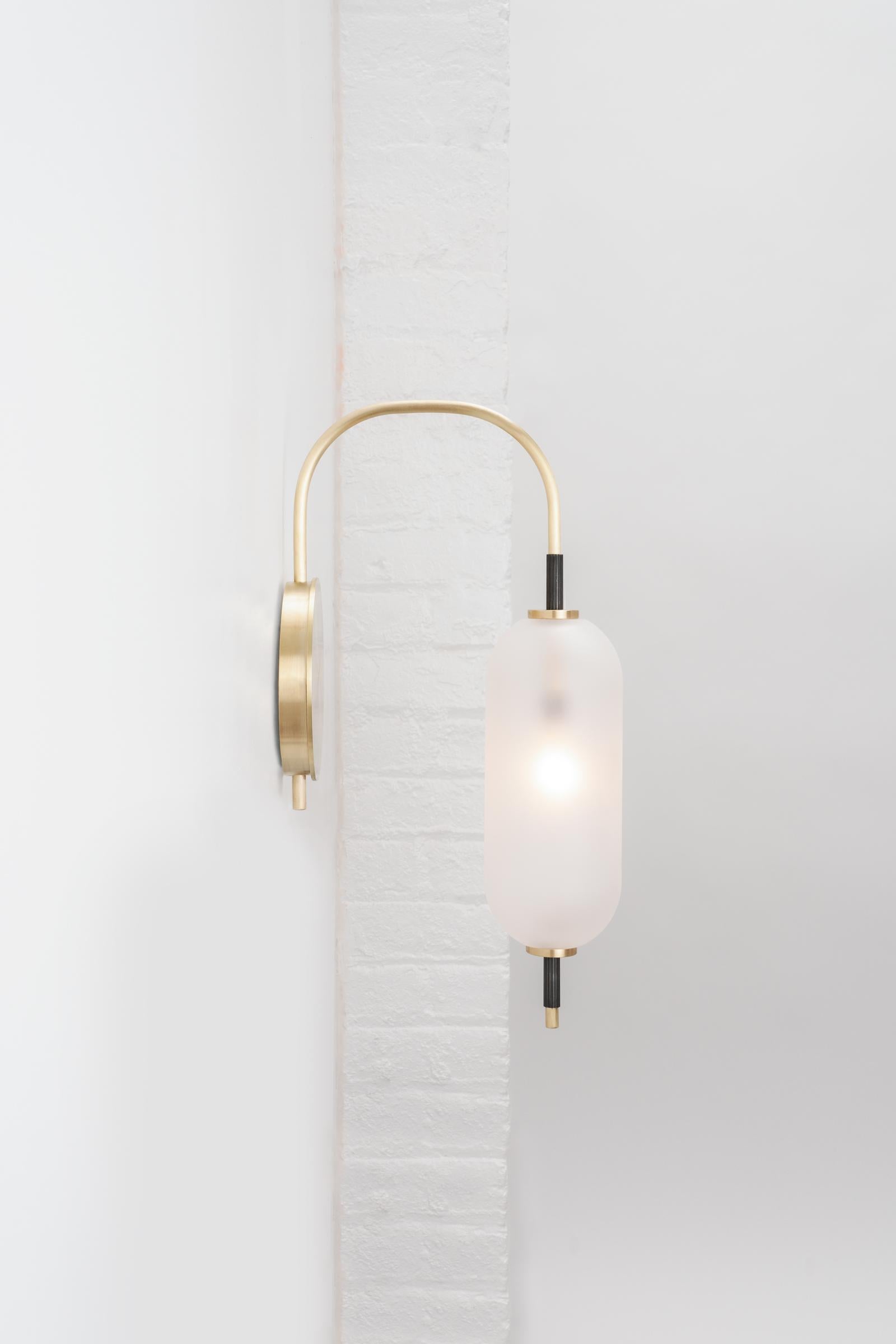 A jewel-like sconce composed of a bent brass stem with sandblasted glass orbs that seem to pierce through them. The bulb inside the glass orb emits a defused glow from the center of its core. 

UL listed.
