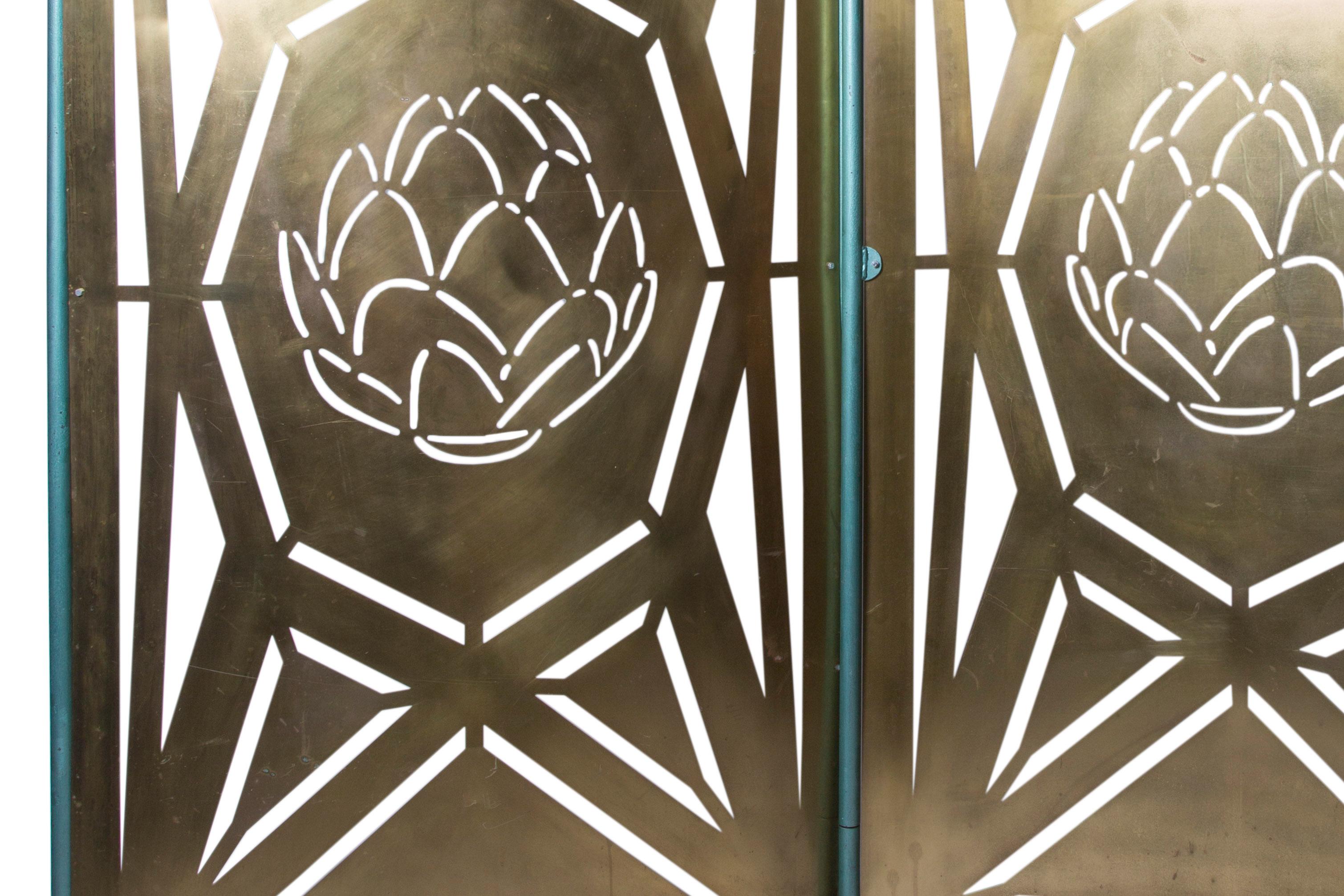 Pierced brass two fold screen or room divider in an industrial Brutalist manner with pierced stylised artichokes to centre of panels. Housed in its original industrial vernacular wheeled frame.