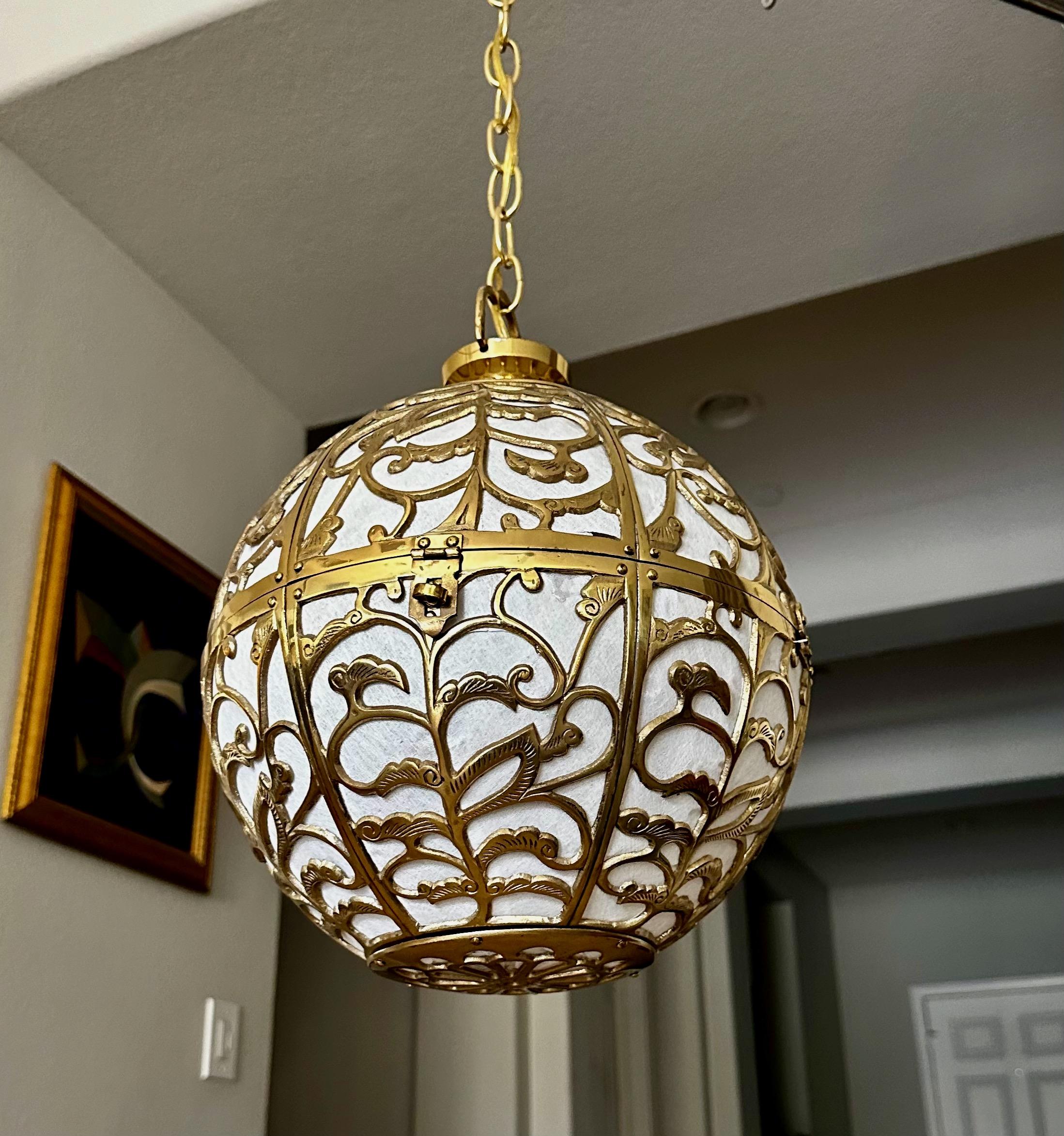Brass pierced Asian chandelier or pendant light with scrolling arabesque pattern motif. Handcrafted from thick solid brass interior covered in rice paper giving the light a diffused soft warm glow. The fixture is near perfect condition, possibly