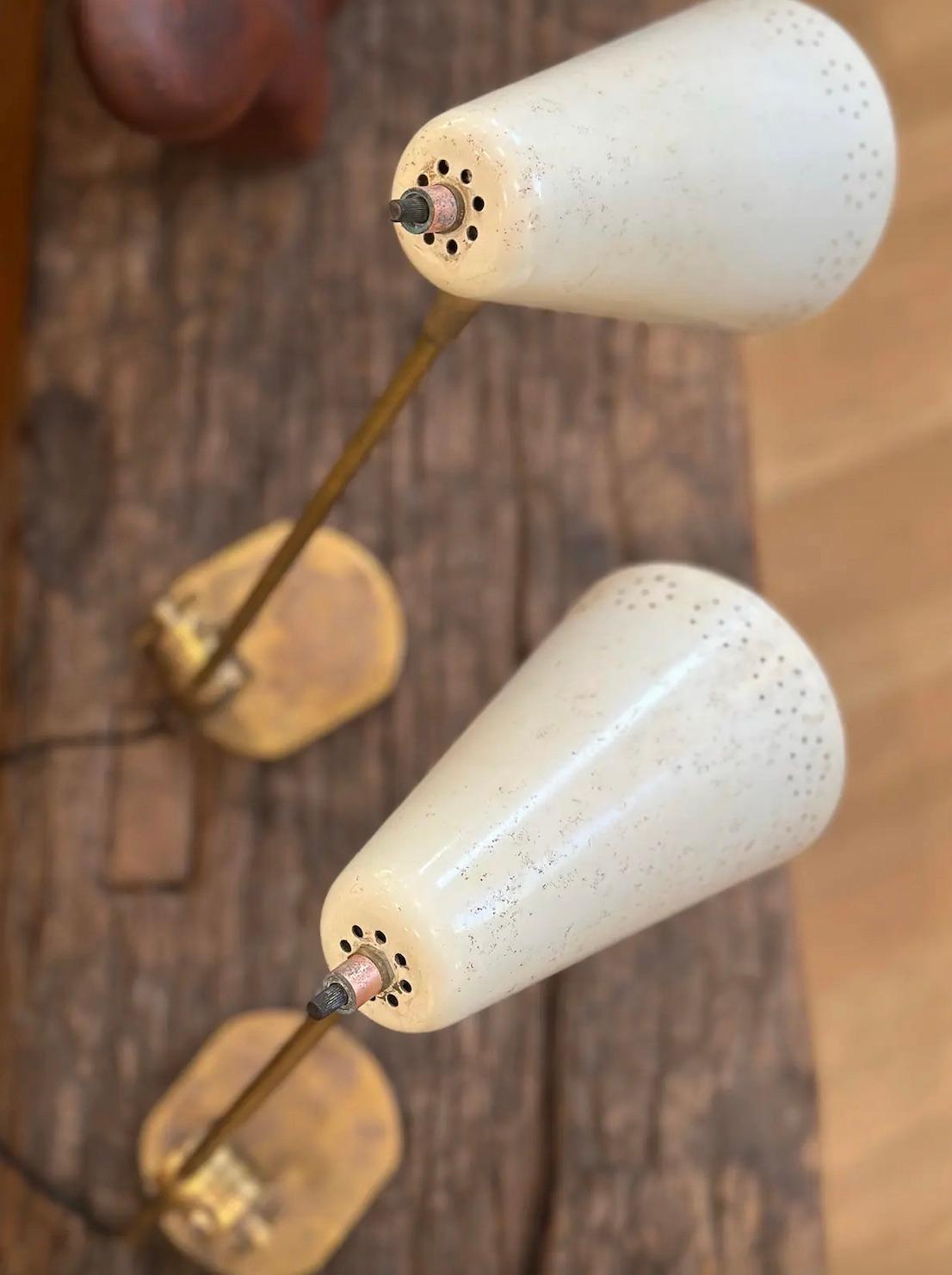 Lampade di metà secolo con meccanismo regolabile alla base. Corpo e base in ottone con paralumi originali forati.
