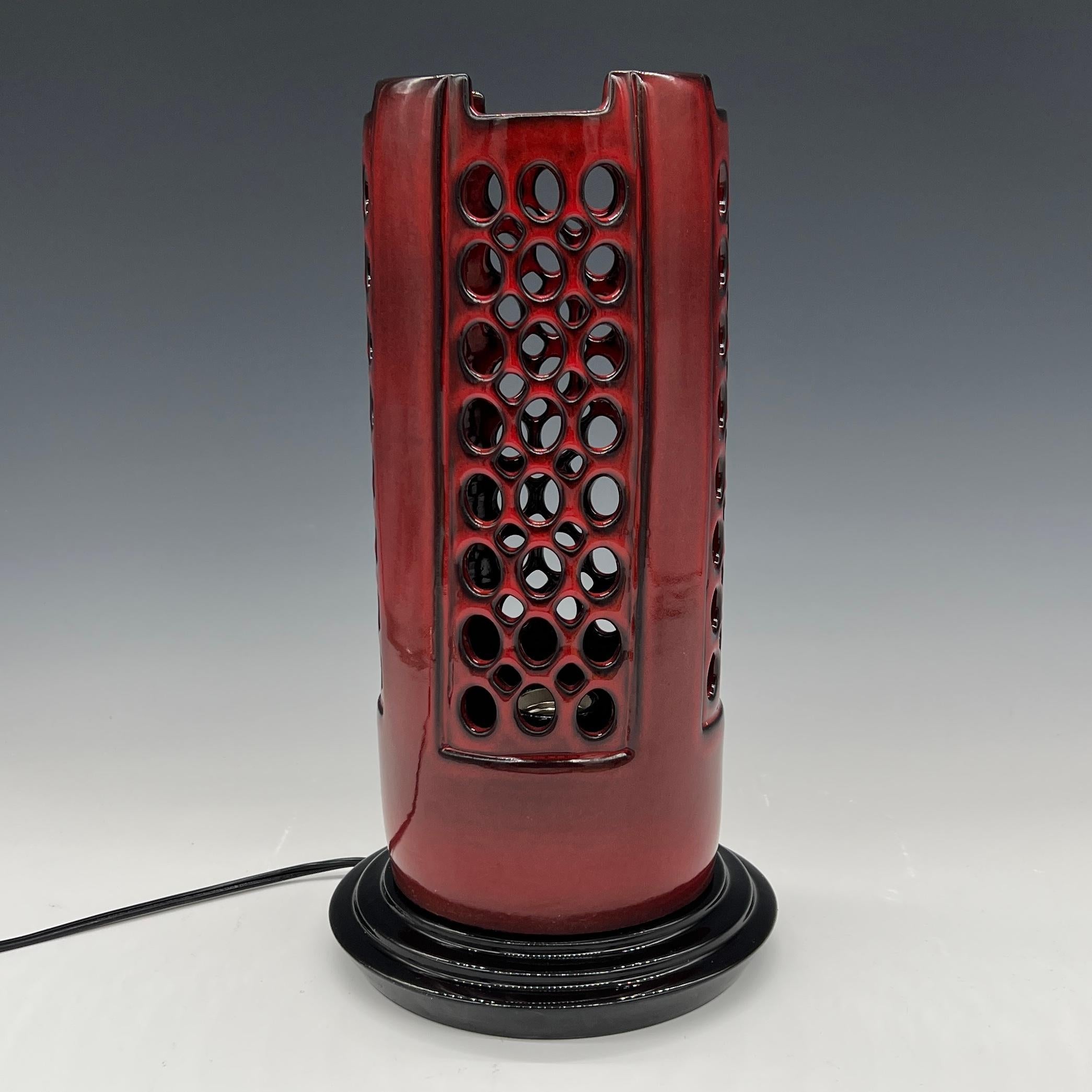Diese Lampe wurde auf der Drehscheibe gedreht und von Hand mit einer leuchtenden, glänzenden roten Glasur versehen, die am Rand und an den Kanten schwarz ausläuft.
Der Sockel ist aus radgedrehter Keramik mit glasig schwarzer Glasur
Schwarzes Kabel