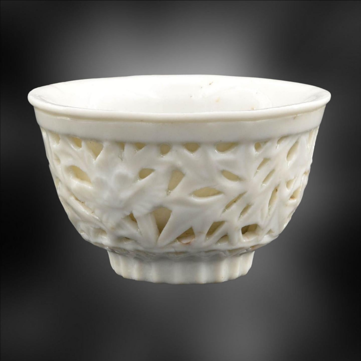 This is a stunning antique Blanc de Chine double walled tea bowl! This elegant piece is perfect for collectors and enthusiasts for antique china. The perforated outer wall is moulded with a beautiful foliated bamboo pattern, showcasing the