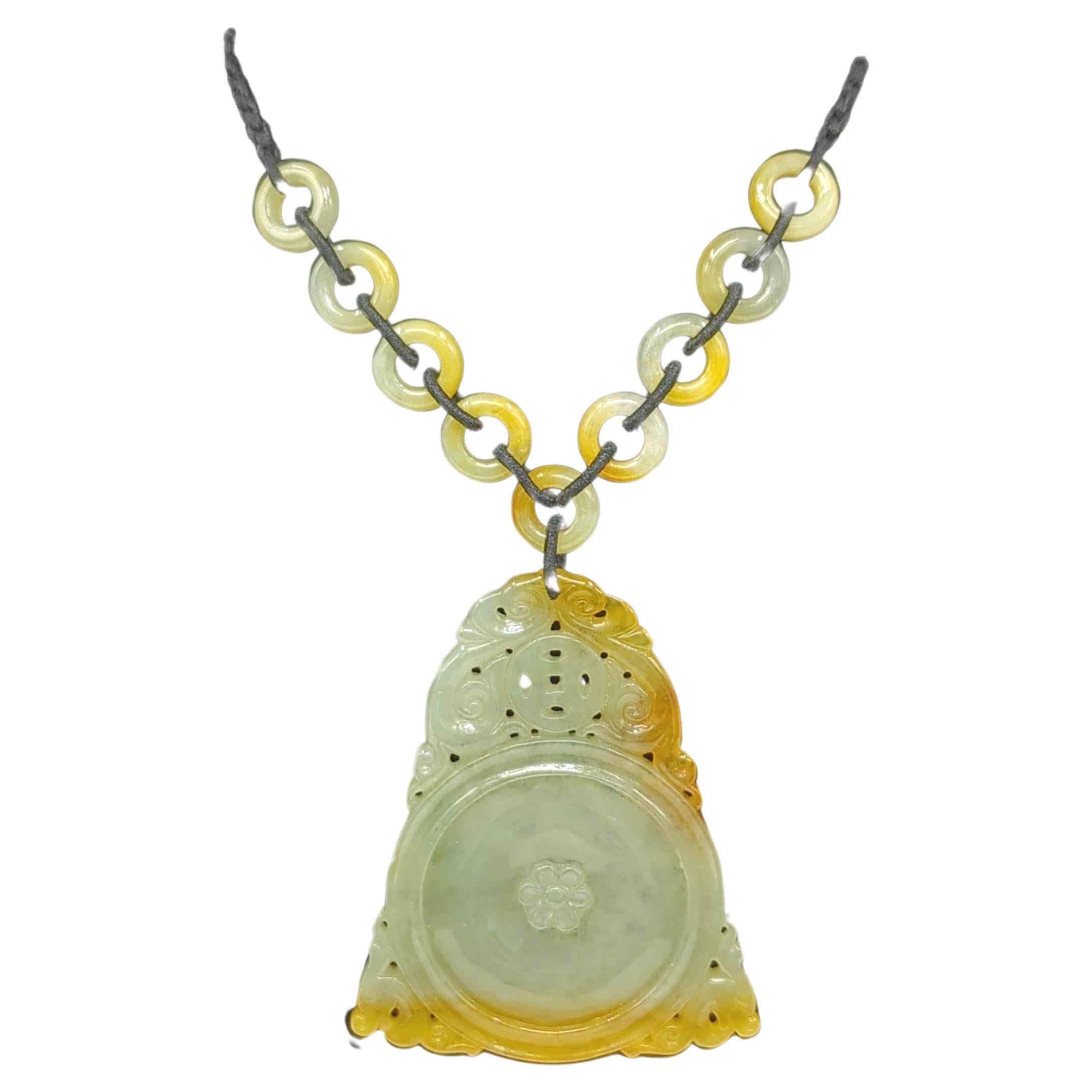 A large finely carved natural yellow jadeite pendant, featuring a carved circular bi with a 6 petal flower center medallion, topped with a coin, surrounded by pierced scrolling ruyi borders, and attached to 9 matching circular jadeite beads on a