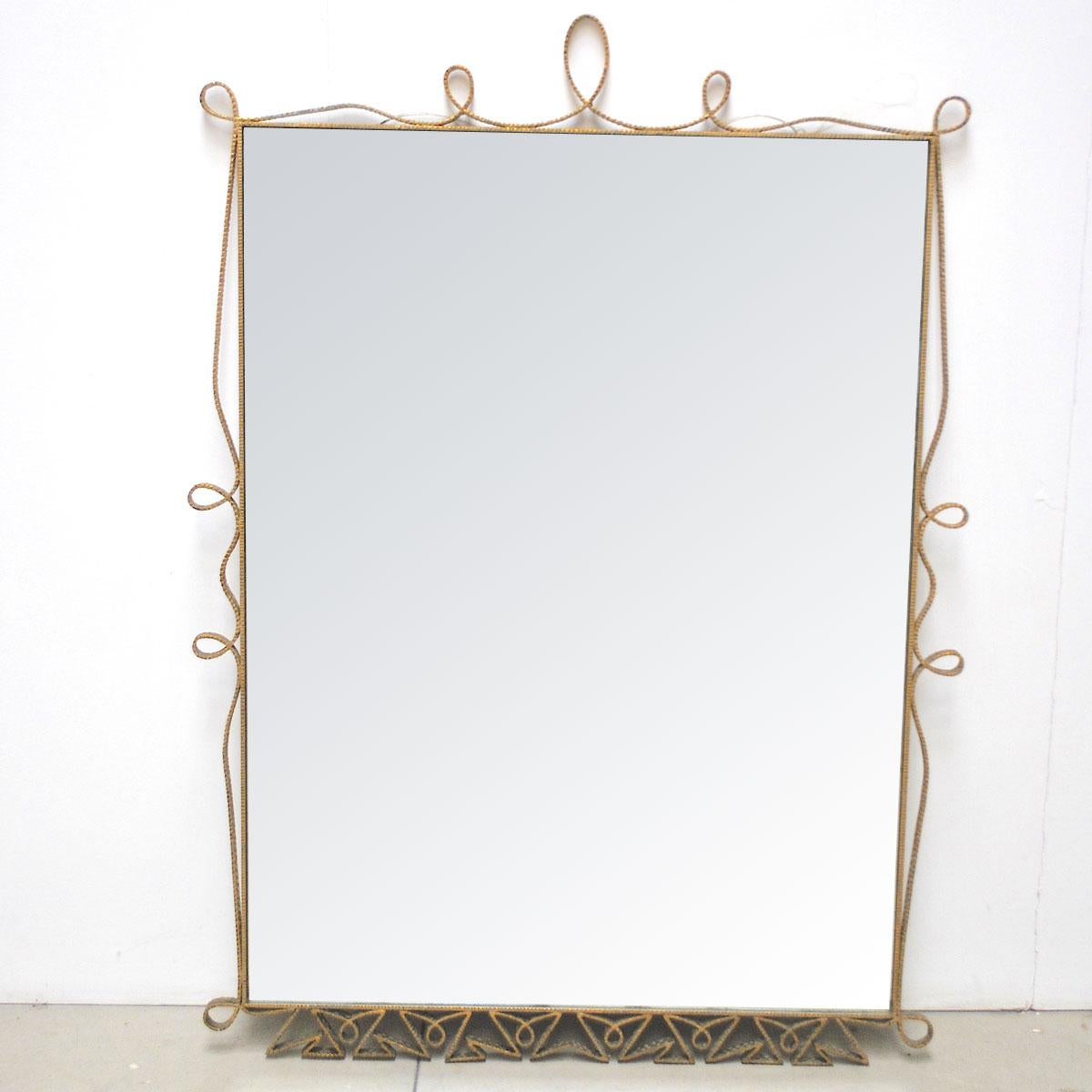 A large and decorative mirror by Pierluigi Colli 1950s in golden wrought metal.