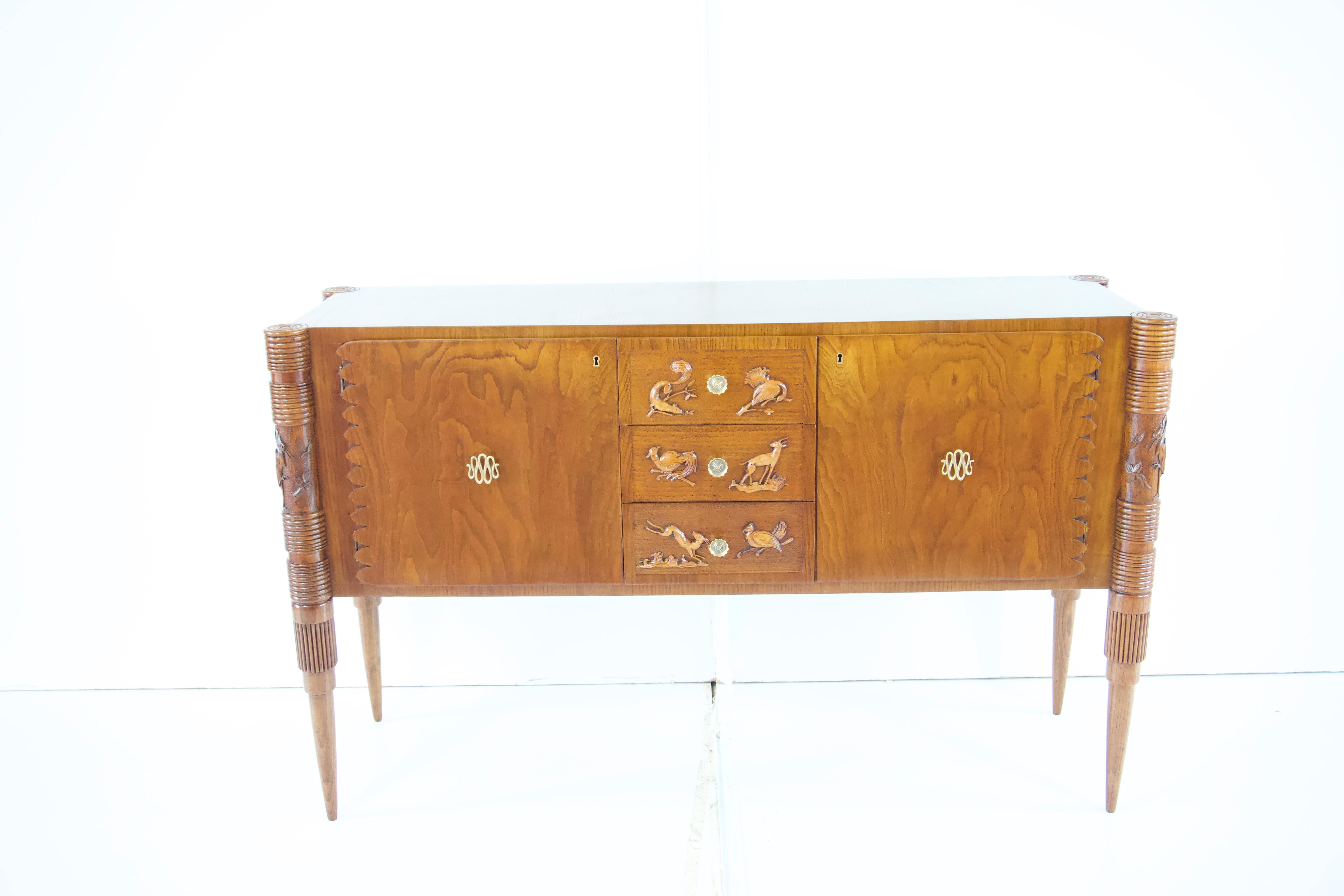  sideboard with a burled birch veneer designed by Pier Luigi Colli in 1940
produced by F.lli Marelli Cantu
two exterior cabinet doors with ribbon design brass door pulls and a scalloped carved edge, centering three drawers with carved bird