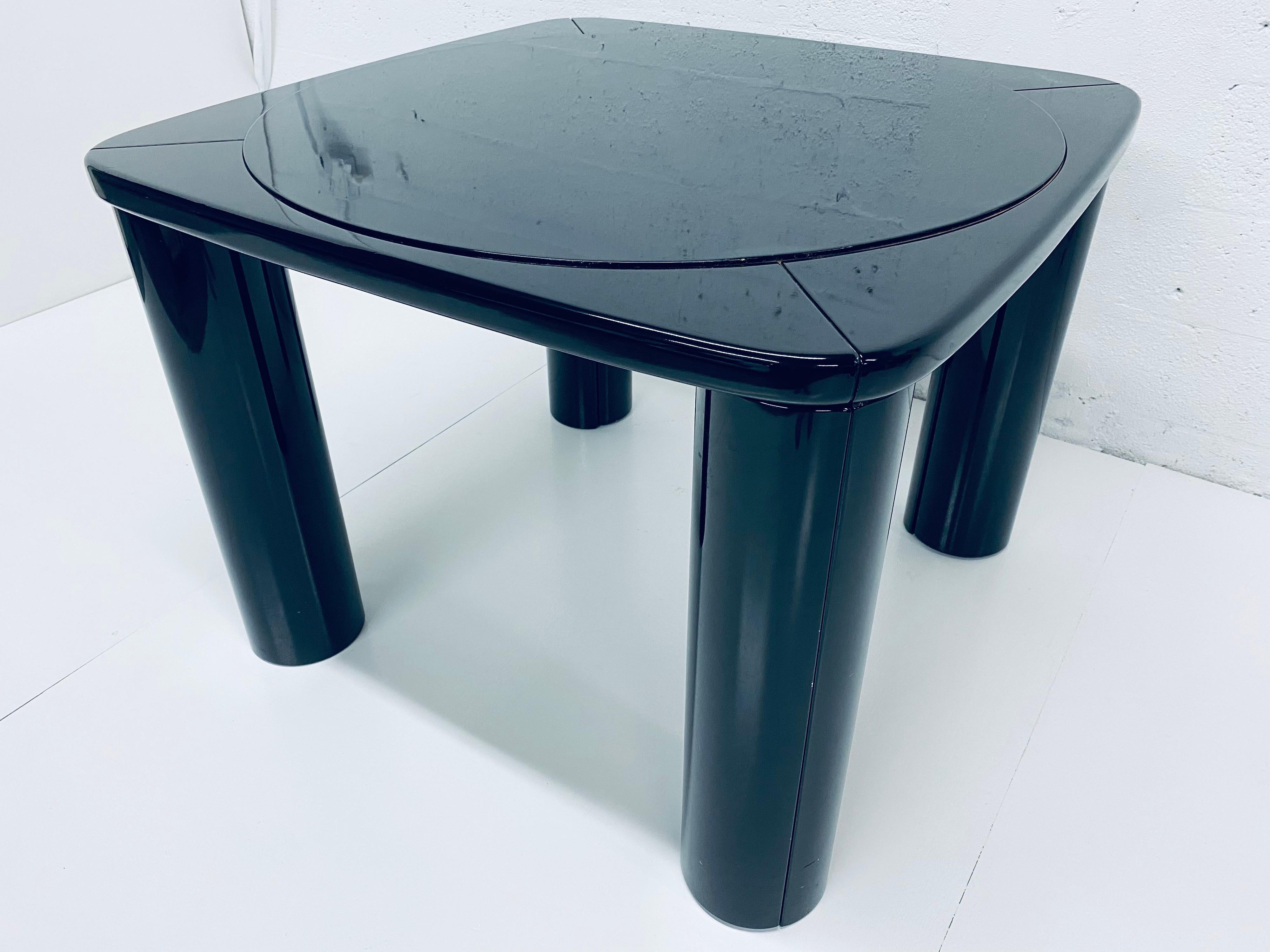 Black lacquered game table designed by Pierluigi Molinari for Pozzi Milano from the 1970s. The top flips over easily revealing a felt backing for playing games while the lacquered side can be used a dining table. The legs open revealing storage for