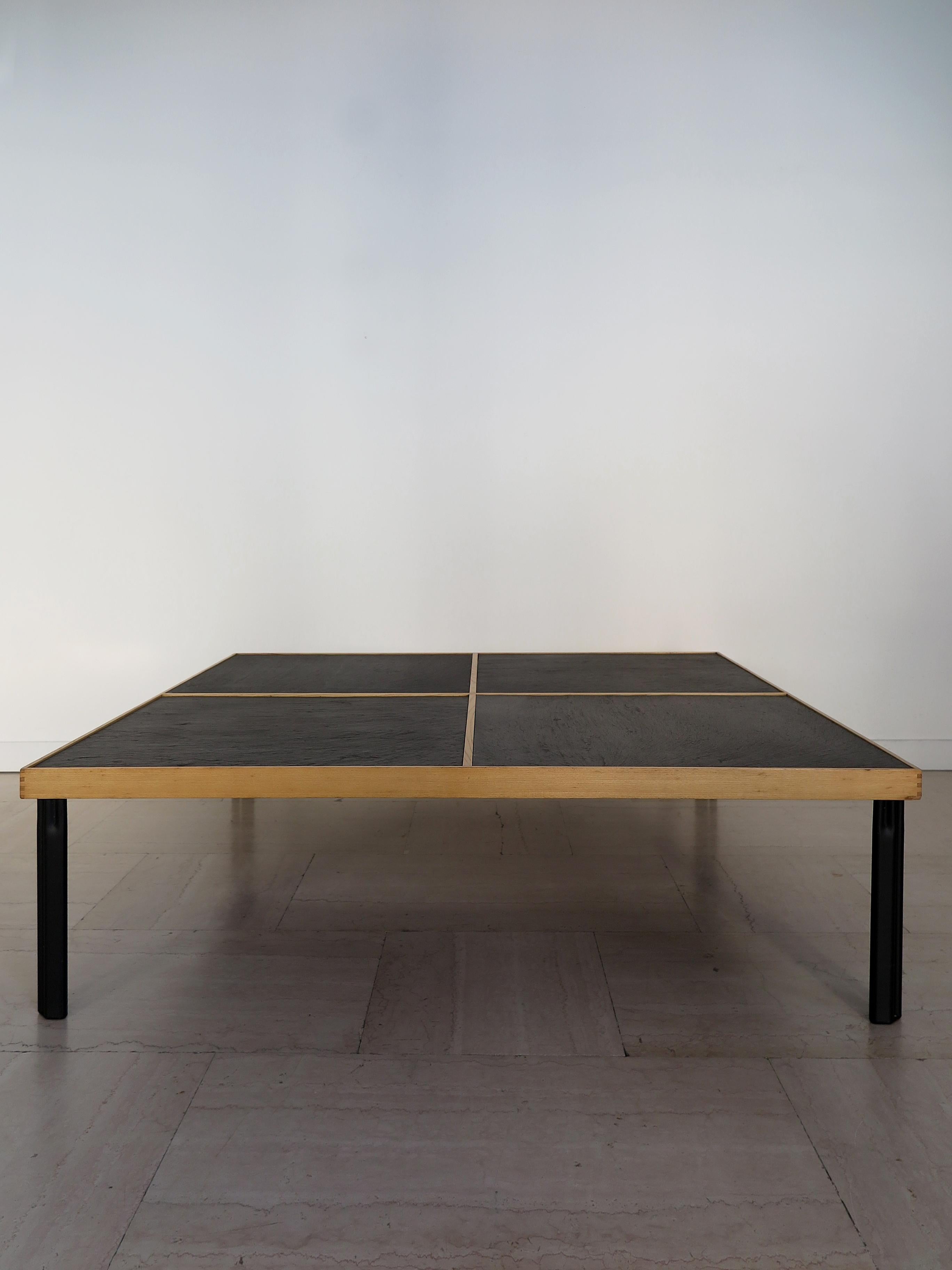 Italian square coffee table from the ‘Naviglio’ series, designed by architect-designer Piero De Martini and produced by Cassina, with a cross-shaped wooden frame with four interlocking slate tops and painted metal legs, manufacturer's adhesive