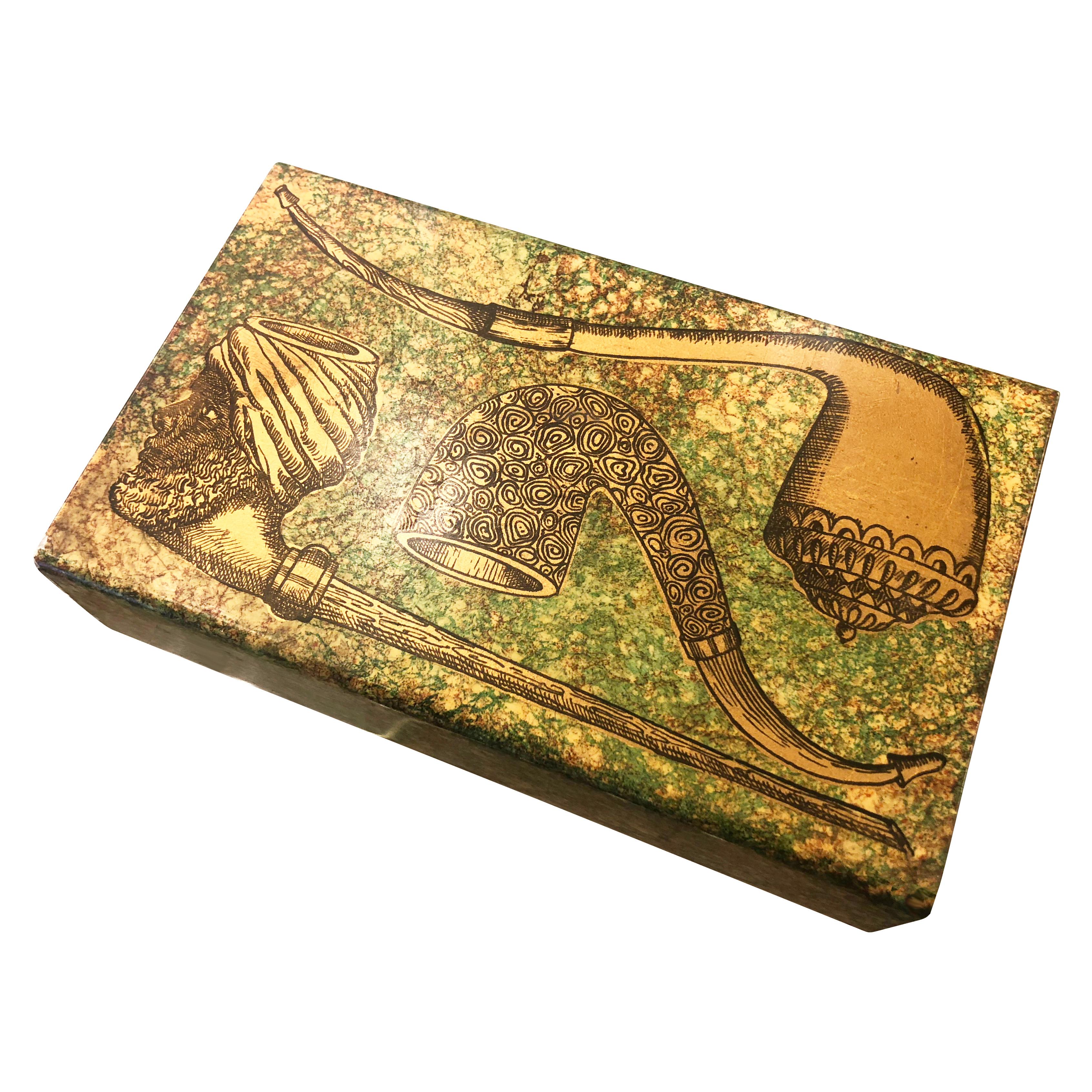 Vintage Piero Fornasetti box featuring a pipe motif. Painted metal cover with sliding wood tray. Felted bottom.

Condition: Excellent vintage condition, minor wear consistent with age and use

Measures: Width 7”

Depth 4.25”

Height 2”.

