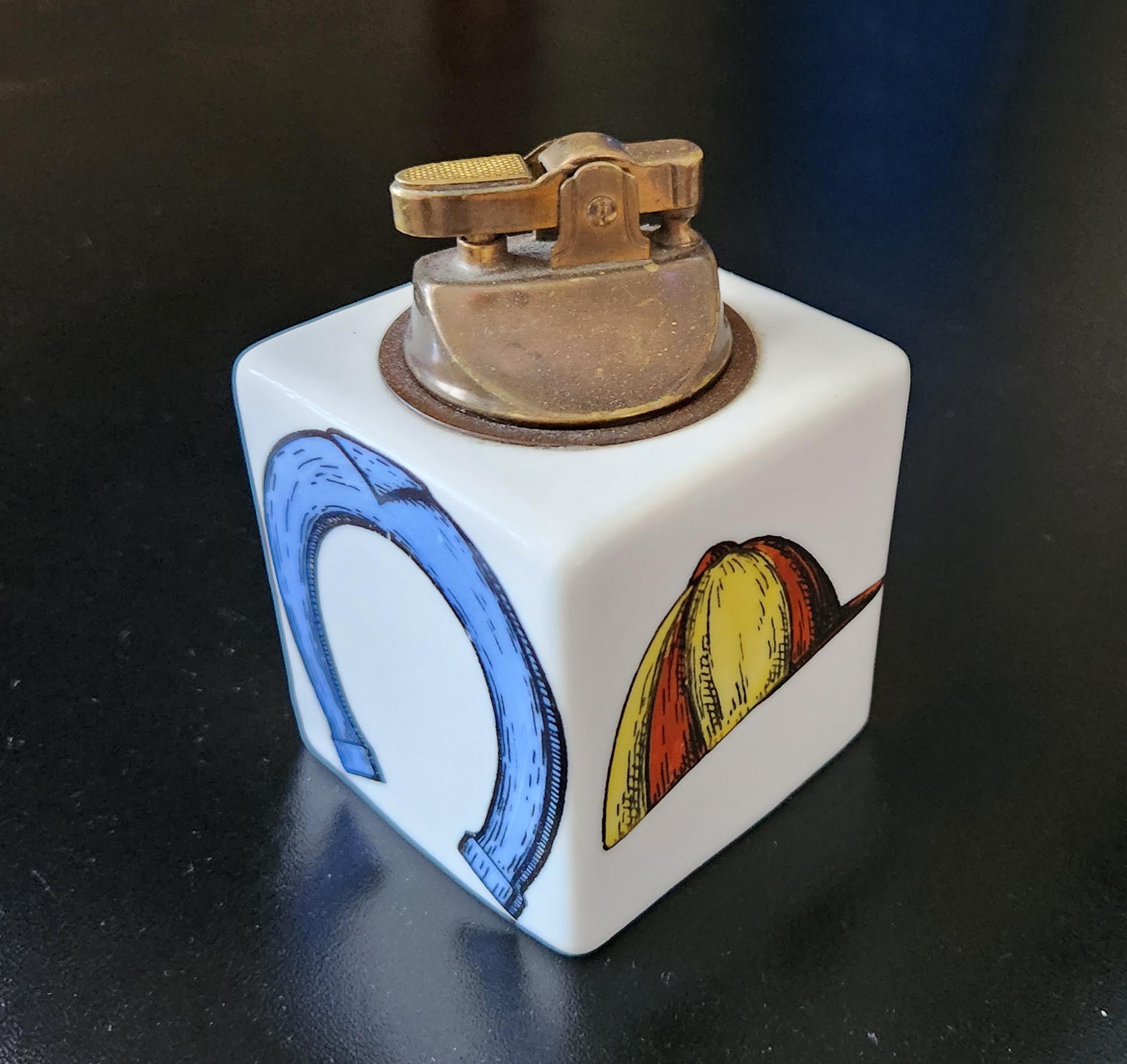 Piero Fornasetti Horse Racing Ceramic Lighter,
Circa 1960s

The Fornasetti ceramic lighter is of square form with images related to horse racing on each side- a horse shoe, a racing jockey cap, a horse bit and a spur.  The interior hollow.  The