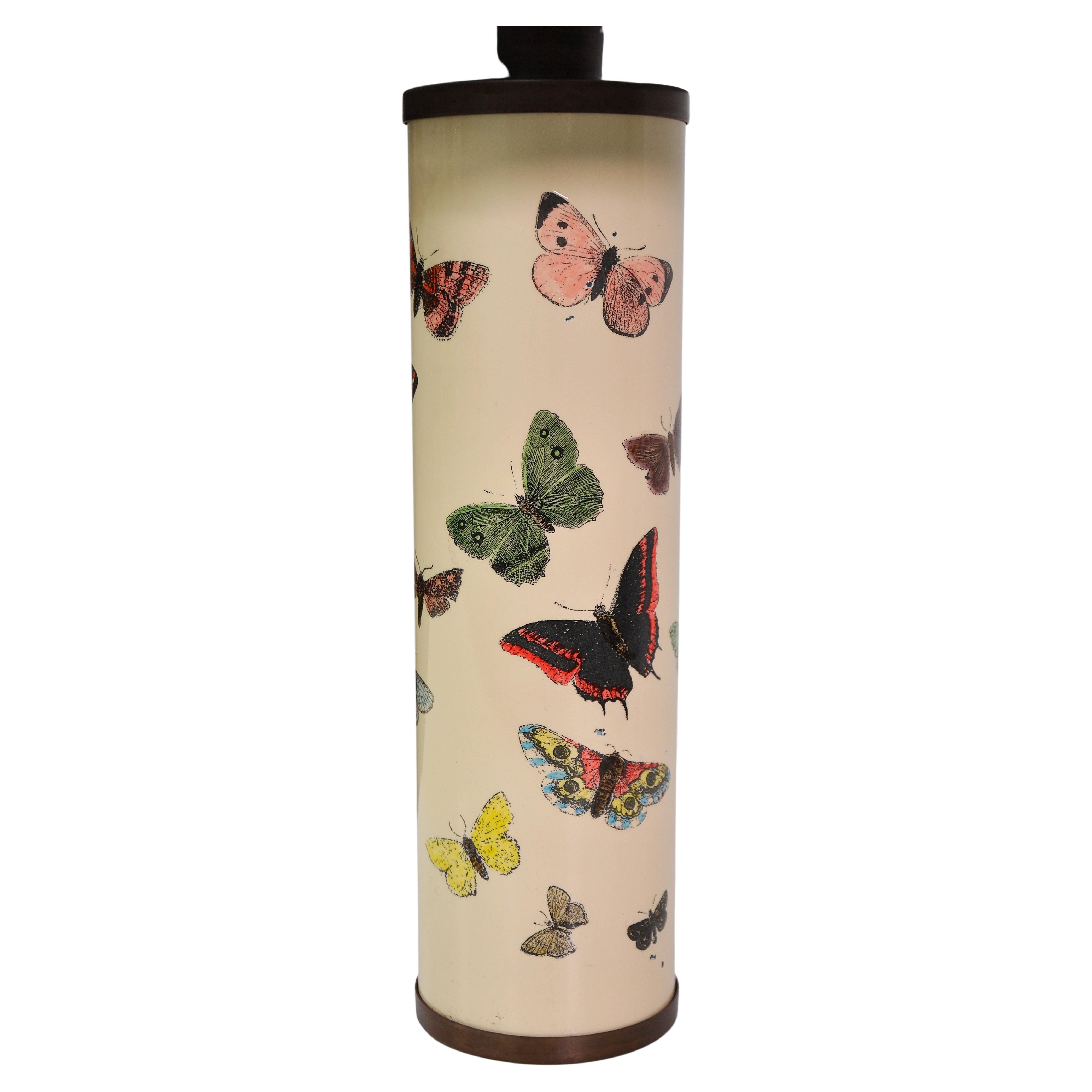 A vintage Mid-Century Modern off-white lamp by the Italian master of playful and surreal self-expression, Piero Fornasetti. The brass lamp features screen-printed green, blue, pink and yellow butterflies on a cream ivory background. Height to socket