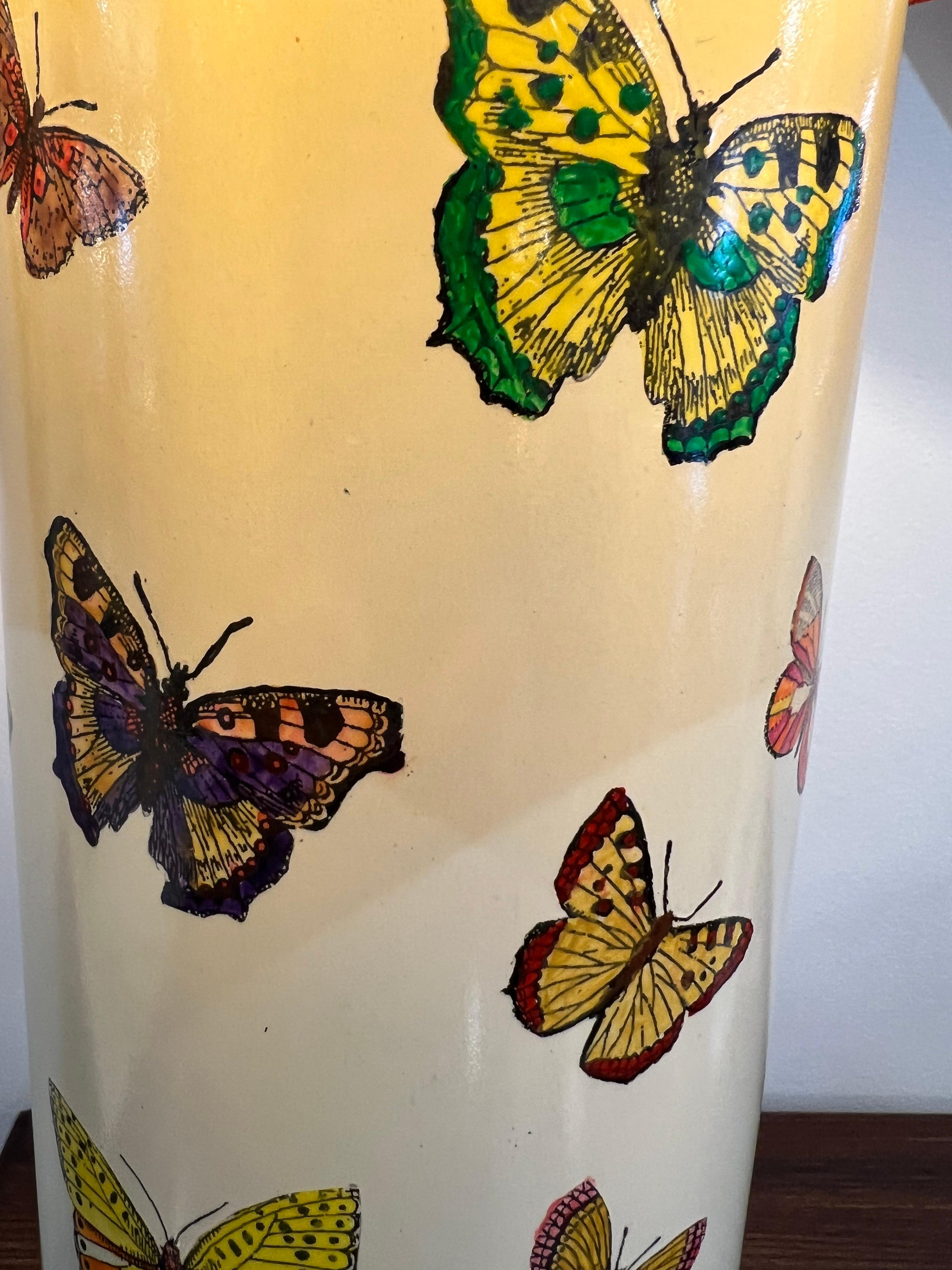 A collectable late 20th century whimsical “Farfalle” design by Piero fornasetti with colourful butterflies set against a cream background with brass accents. The lamp is labelled at the base and comes with a new custom made burnt orange shade with